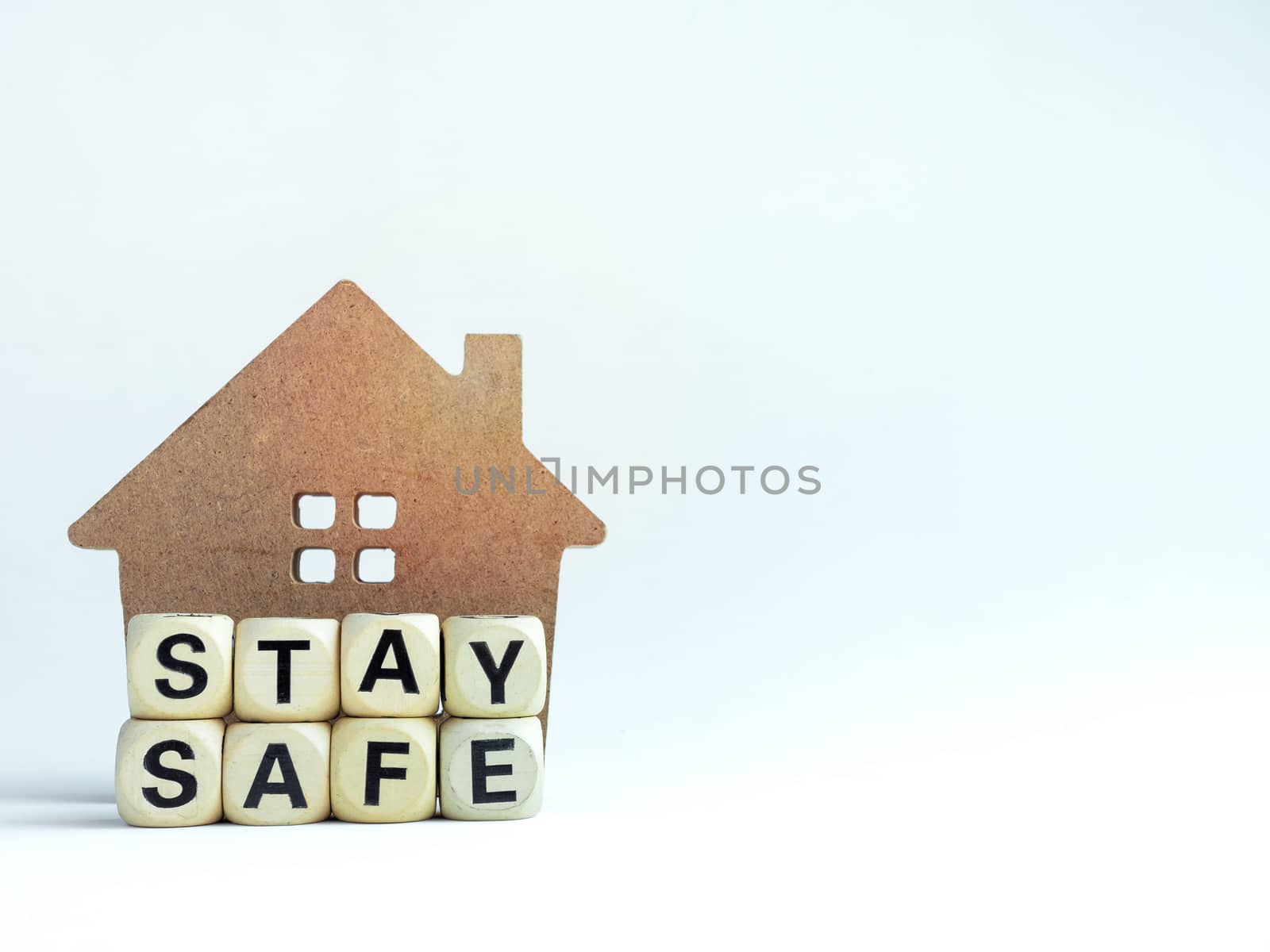 Stay safe concept. Word "Stay Safe" with wooden house isolated on white background with copy space, stay at home, social media campaign for covid-19 or coronavirus pandemic prevention.