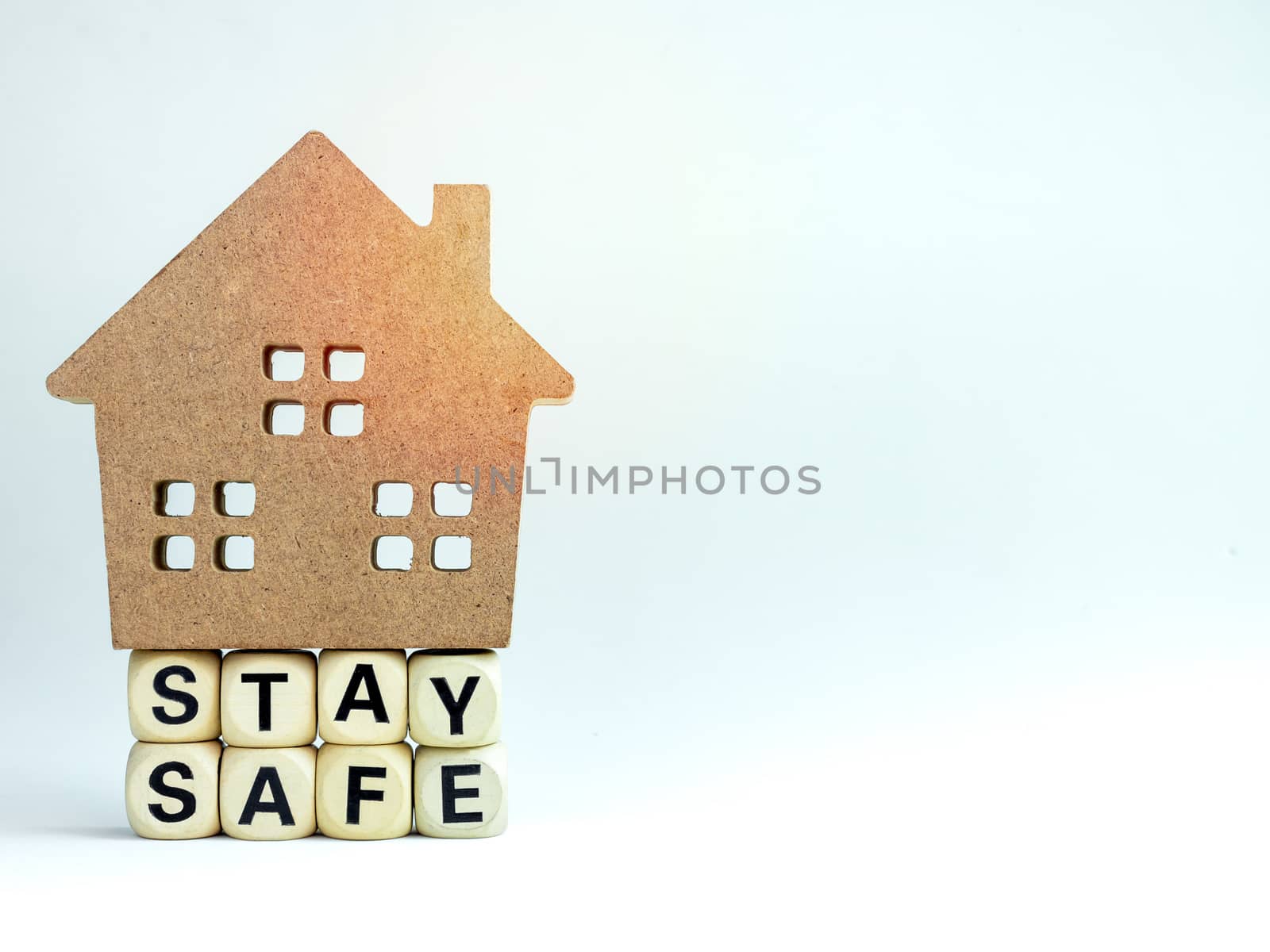 Stay safe concept. Word "Stay Safe" with wooden house isolated on white background with copy space, stay at home, social media campaign for covid-19 or coronavirus pandemic prevention.
