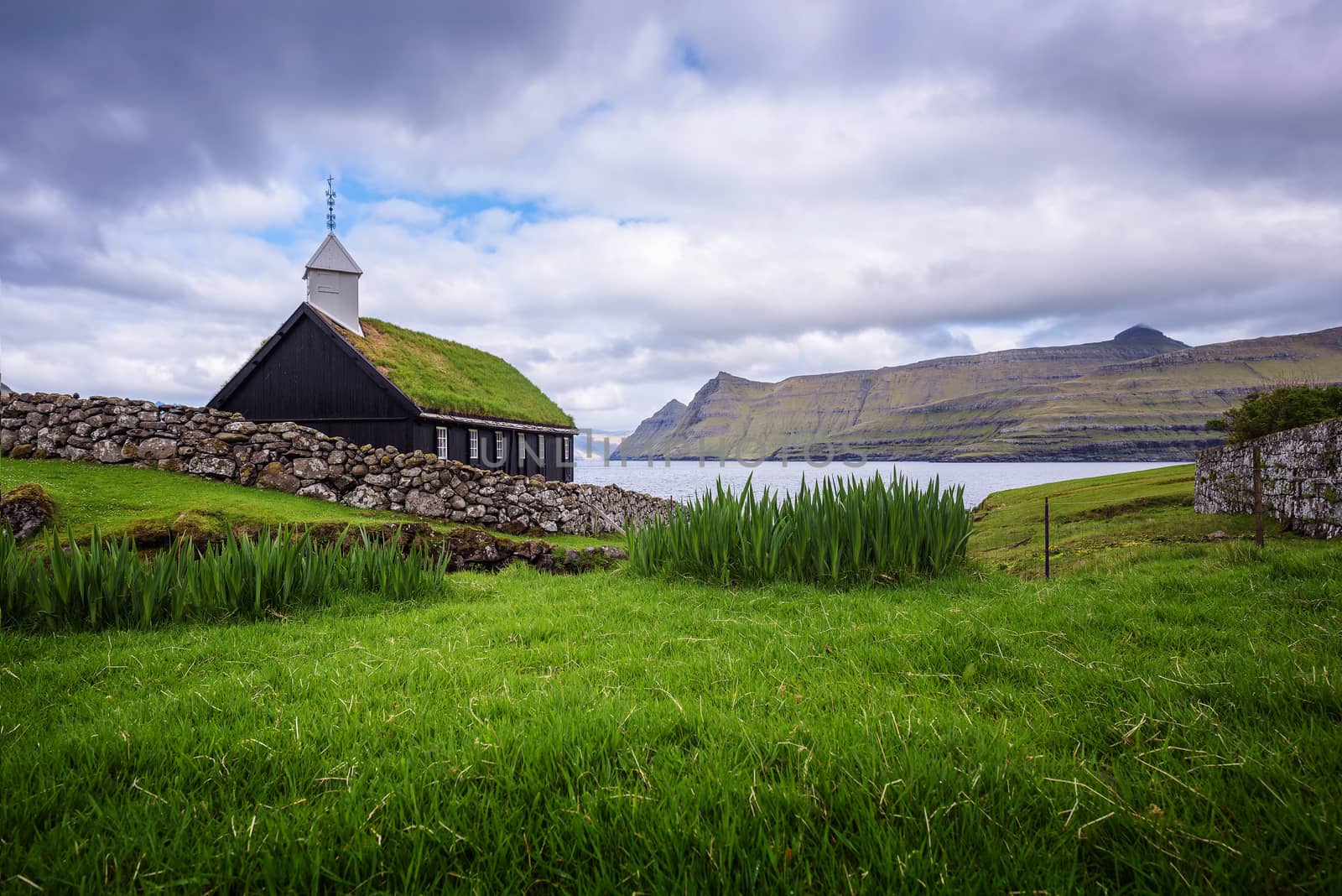Small black wooden church in the village of Funningur situated on the sea shore. Funningur is located on the island of Eysturoy, Faroe Islands, Denmark