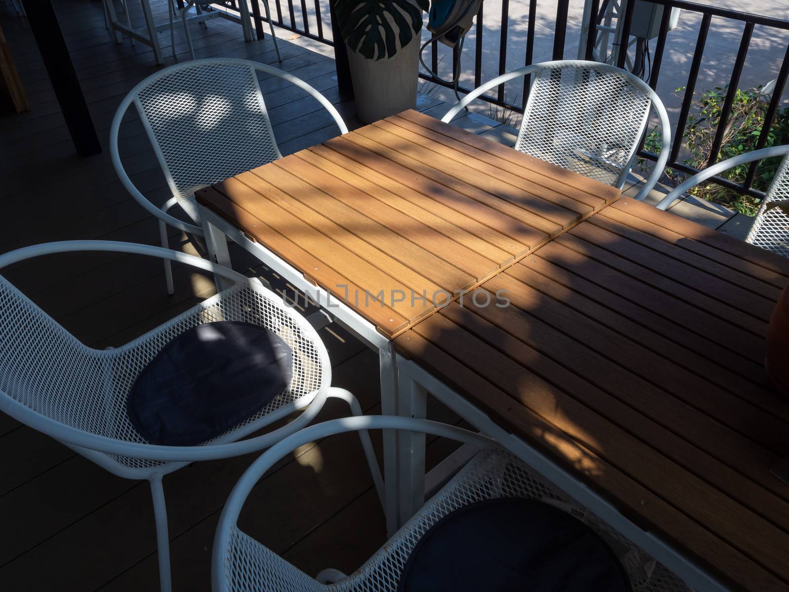 Wooden table and white retro style armchair in terrace. Shady place for relaxation.