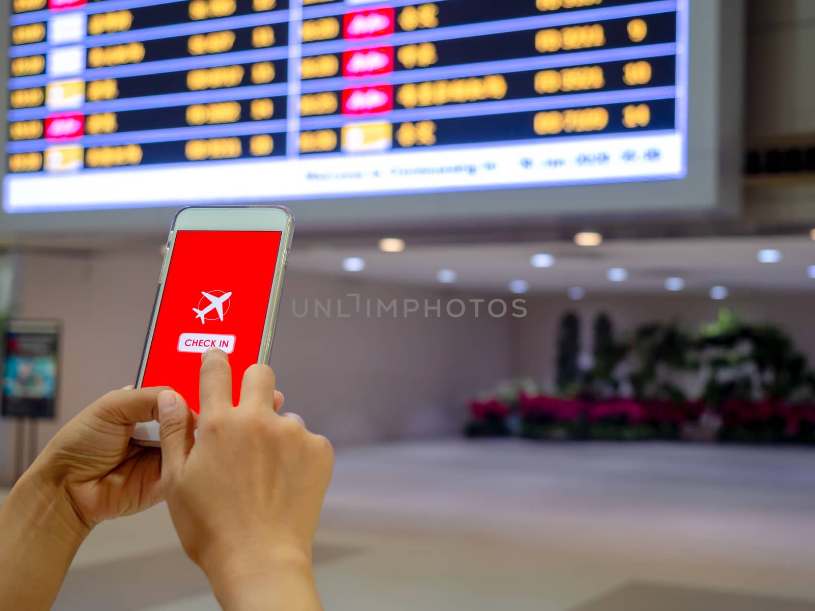 Flight check-in by mobile phone. Hand touching on smartphone screen to check-in for a flight in terminal airport.