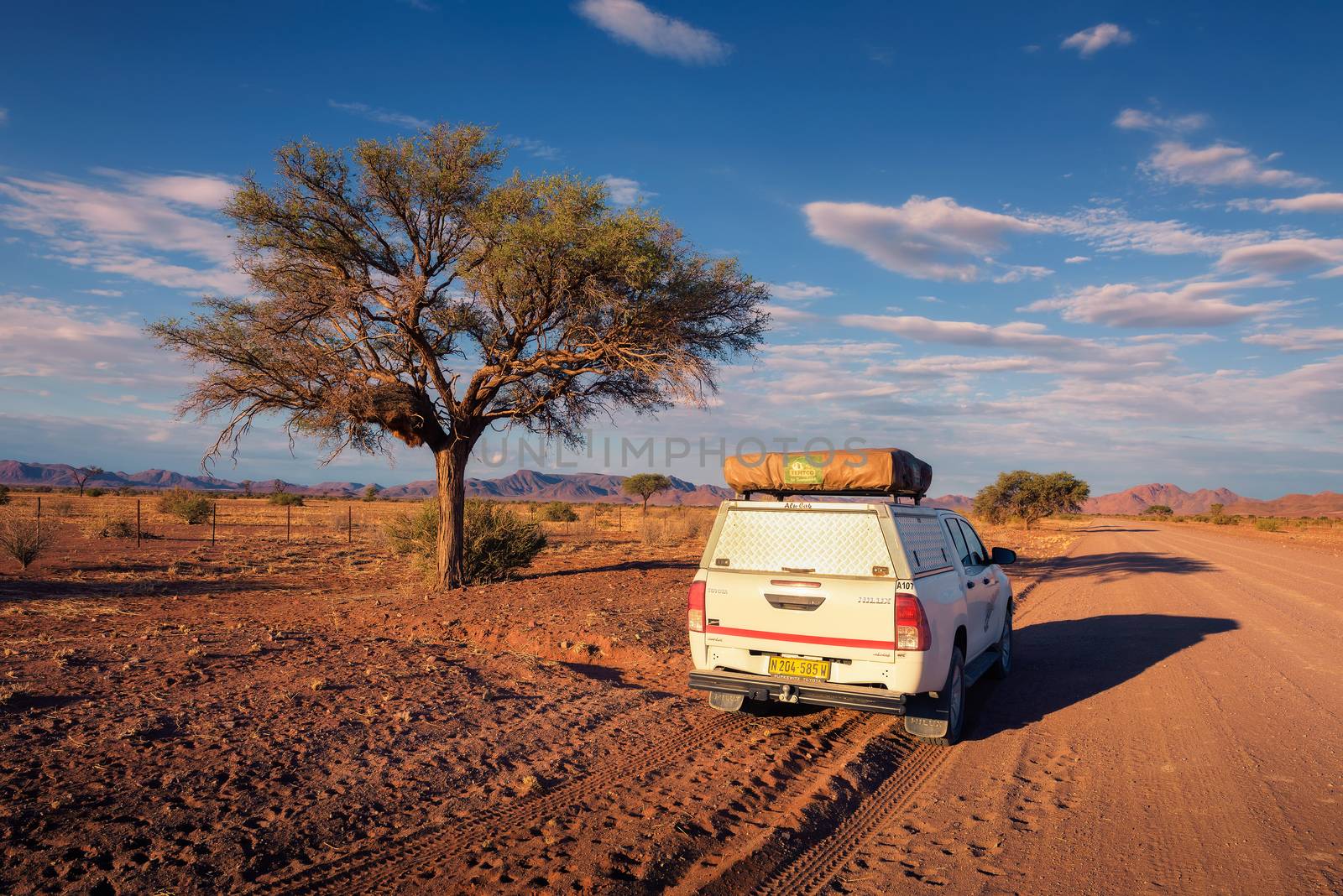 Karas, Namibia - March 30, 2019: Typical 4x4 rental car in Namibia equipped with camping gear and a roof tent driving on a dirt road through Karas Region in Namibia.