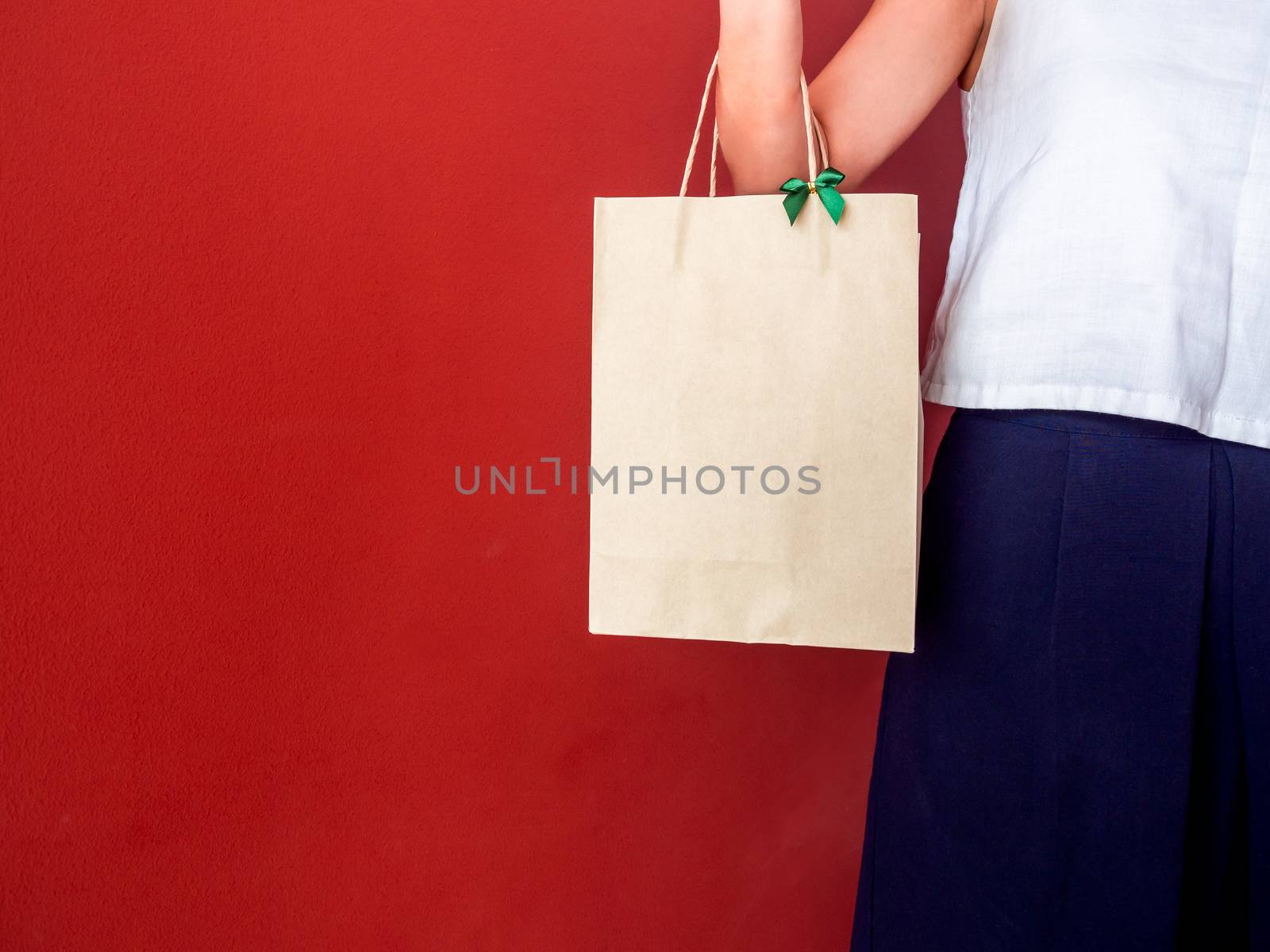 Woman's hand holding blank recycled paper bag decorate with gree by tete_escape