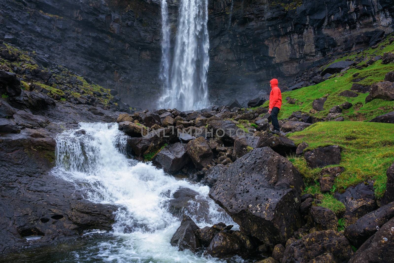 Tourist standing at the Fossa Waterfall on island Bordoy in the Faroe Islands, Denmark