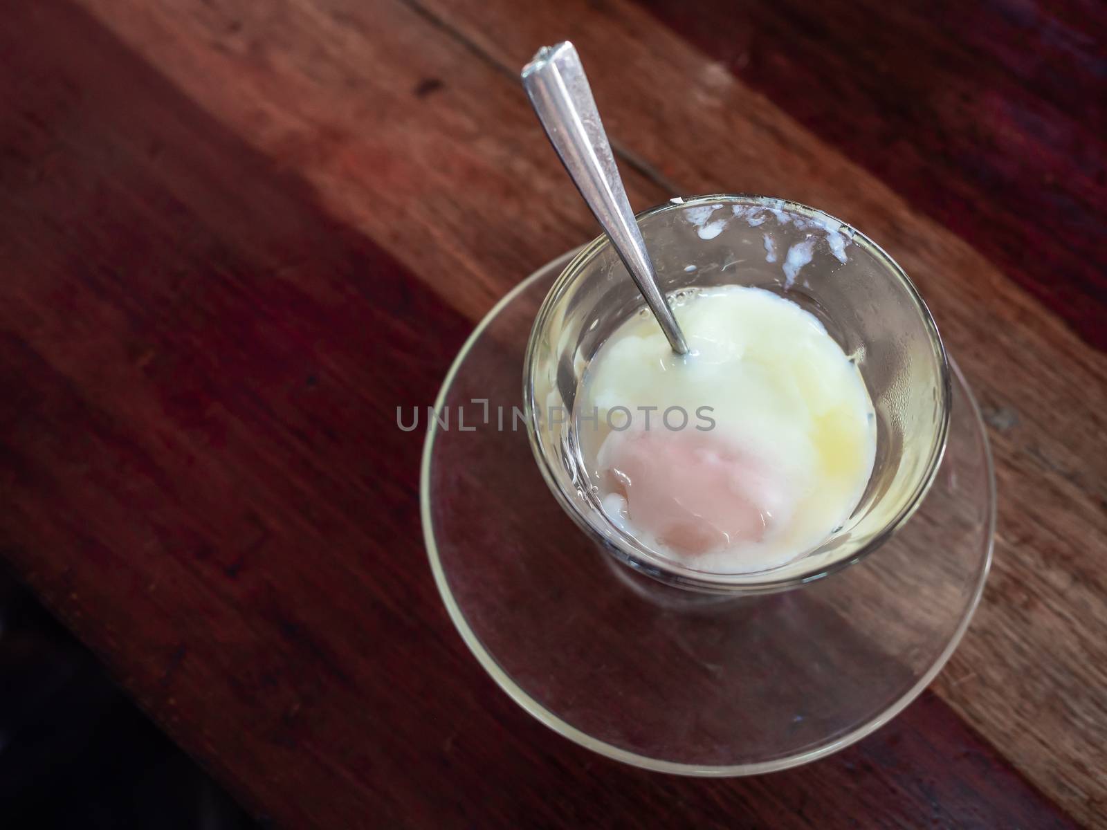 Soft-boiled eggs in glass with spoon on wooden table background top view.