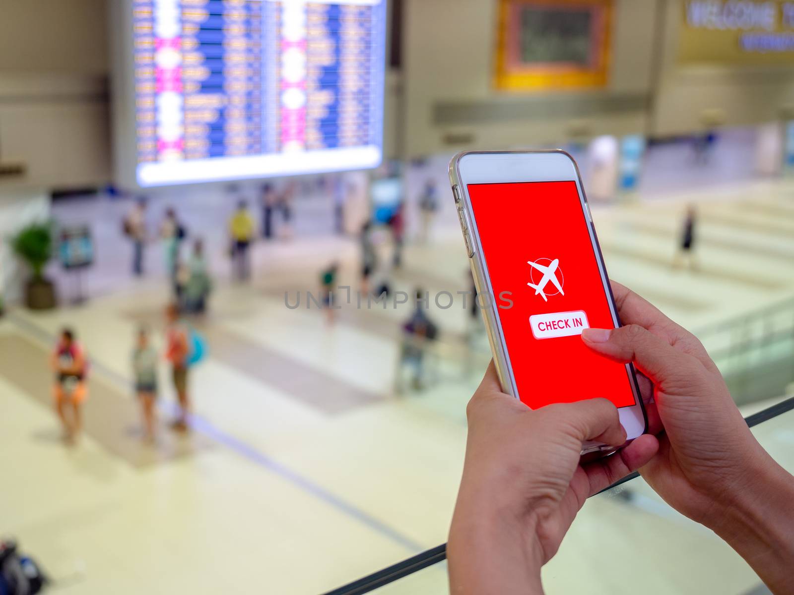 Flight check-in by mobile phone. Hand touching on smartphone screen to check-in for a flight in terminal airport.