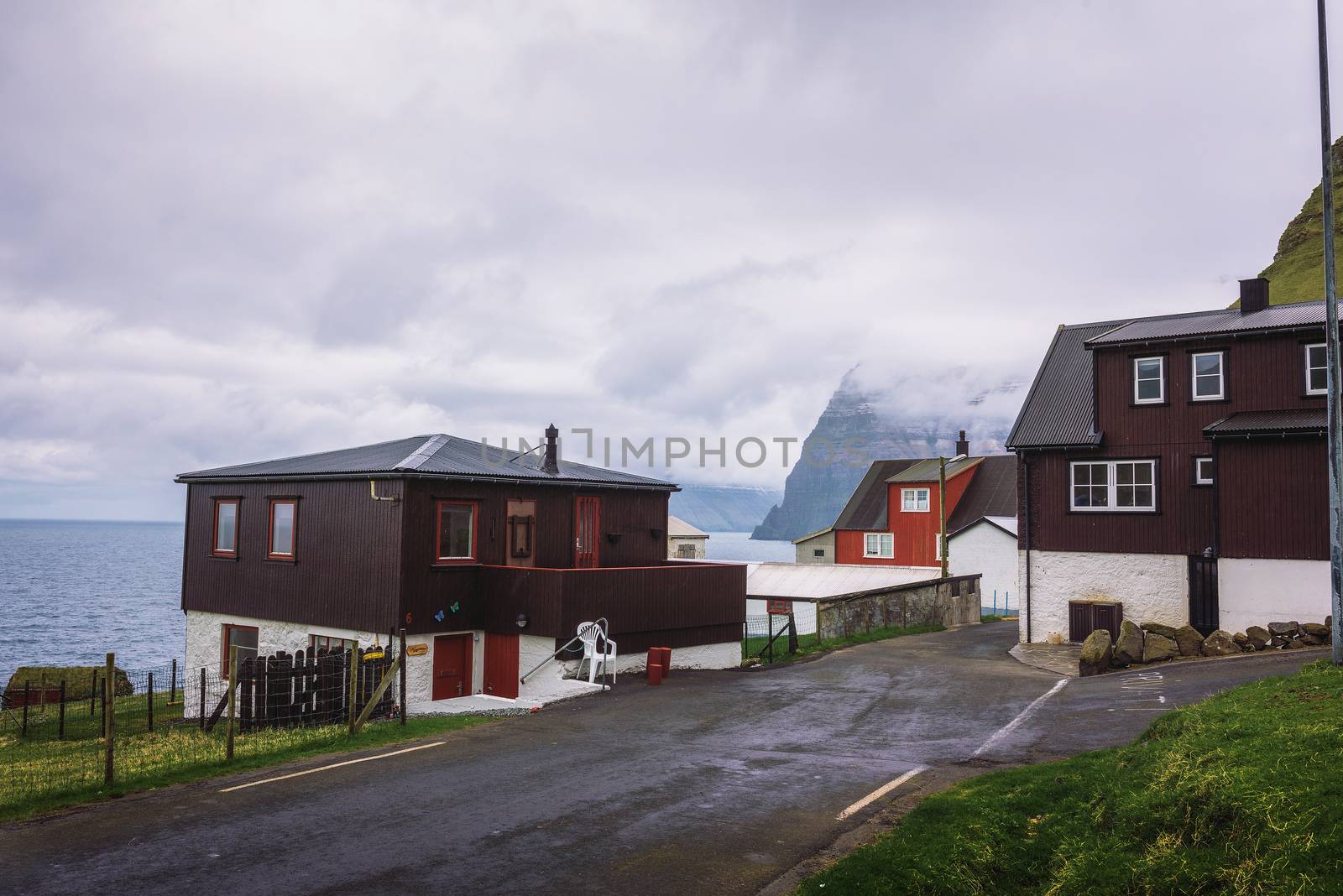 Trollanes, Faroe Islands, Denmark - May 27, 2019 : Small village of Trollanes located on the island of Kalsoy with huge cliffs of neighboring islands in the background.
