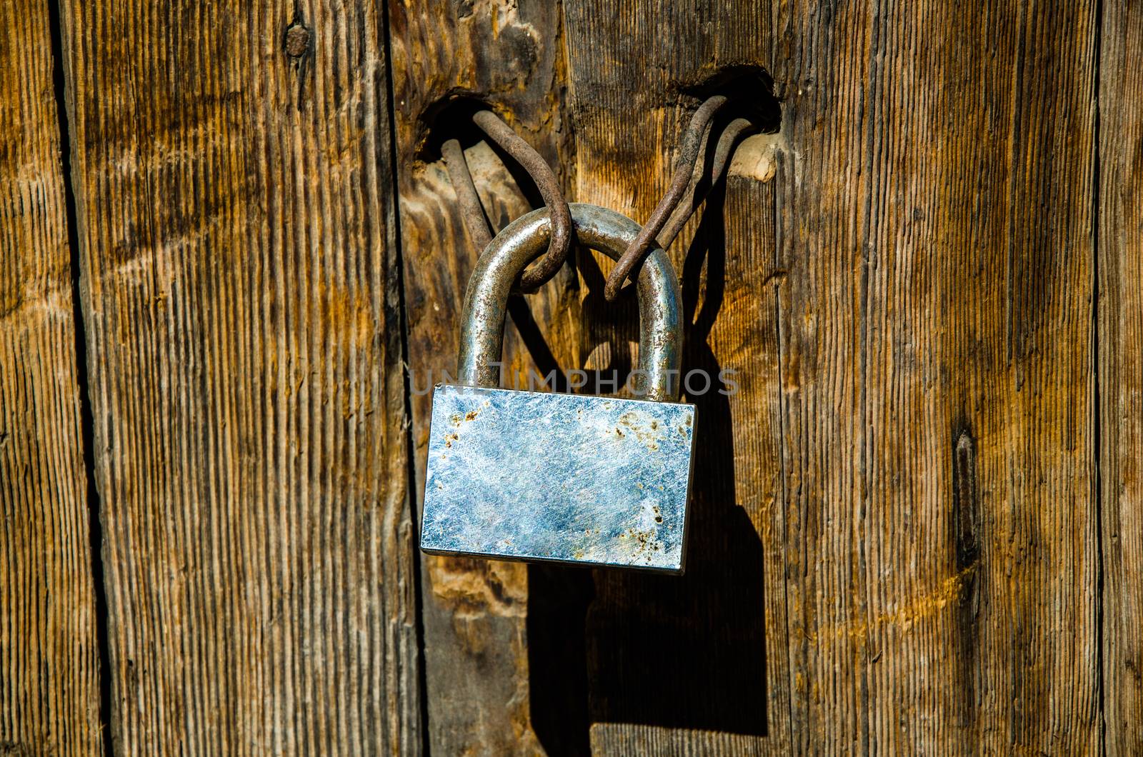 Rusty padlock on an old and deteriorated door