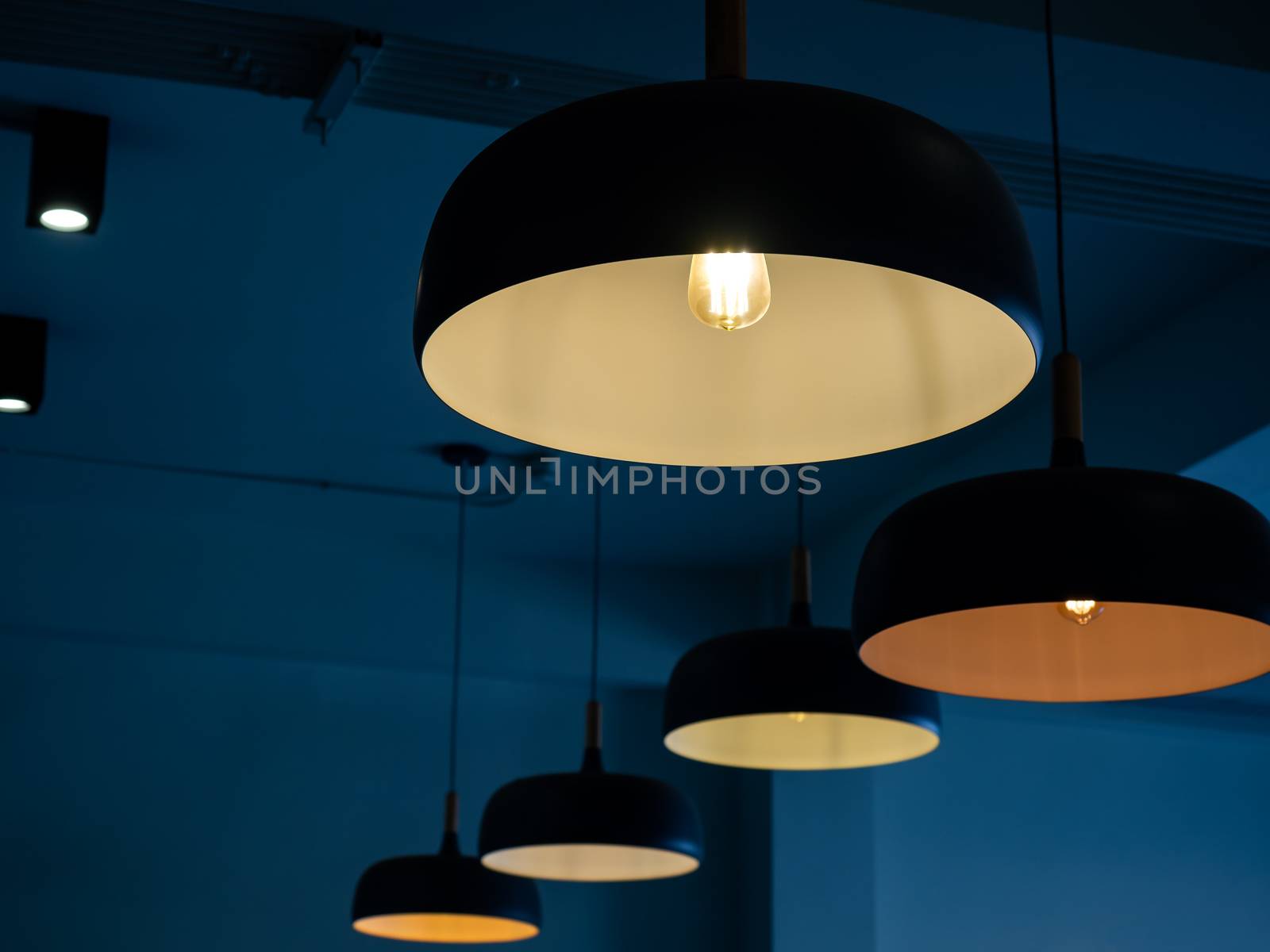 Beautiful round modern ceiling lamps with light bulbs in dark blue room background.