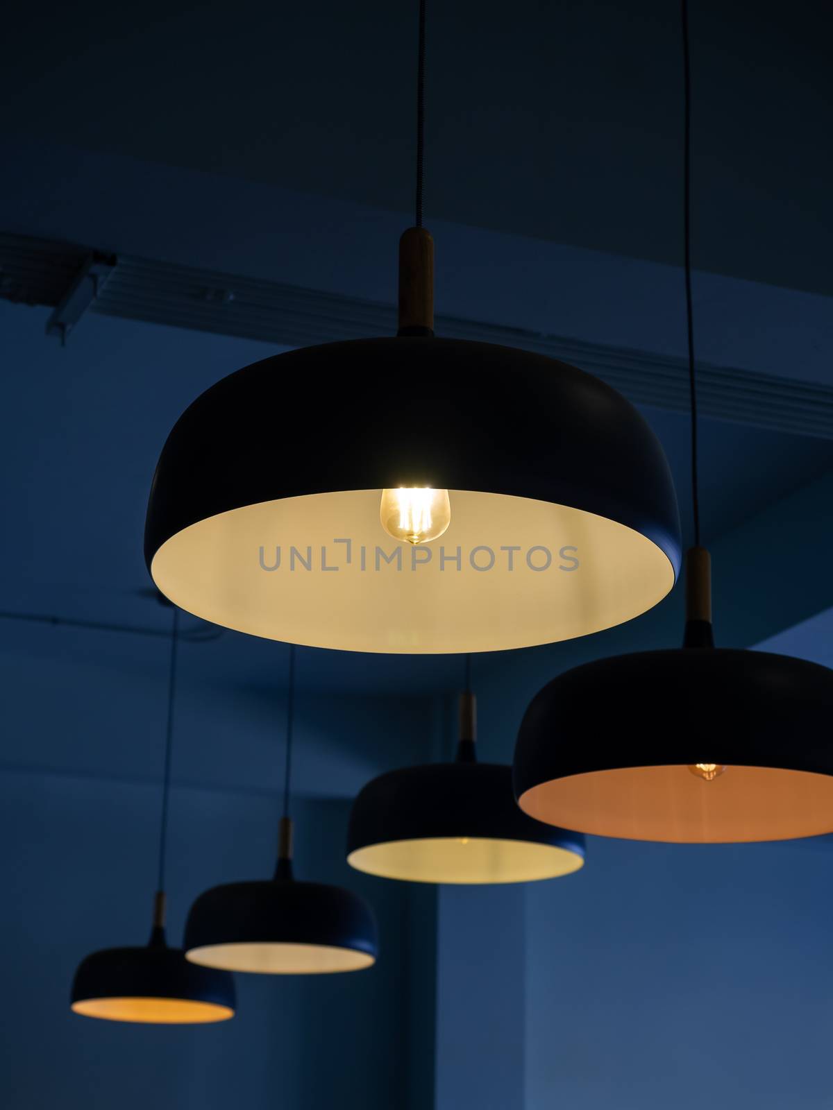 Beautiful round modern ceiling lamps with light bulbs in dark blue room background vertical style.