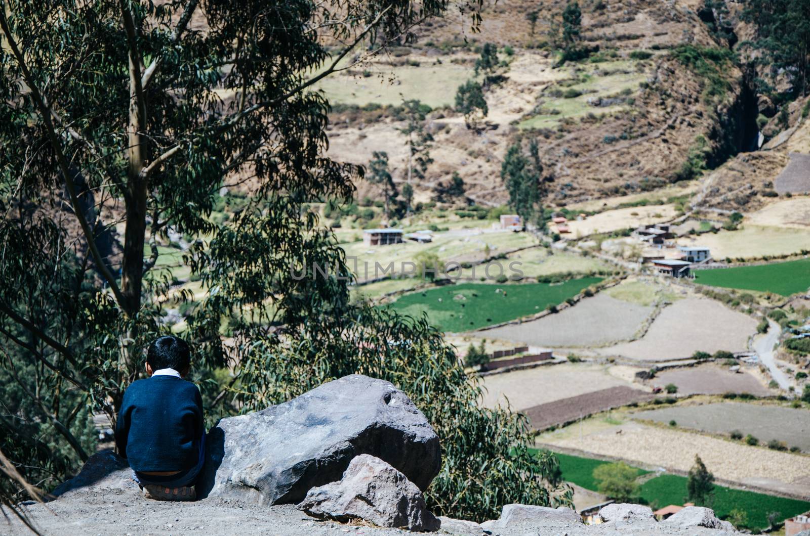 Child sitting on his back on the top of a mountain