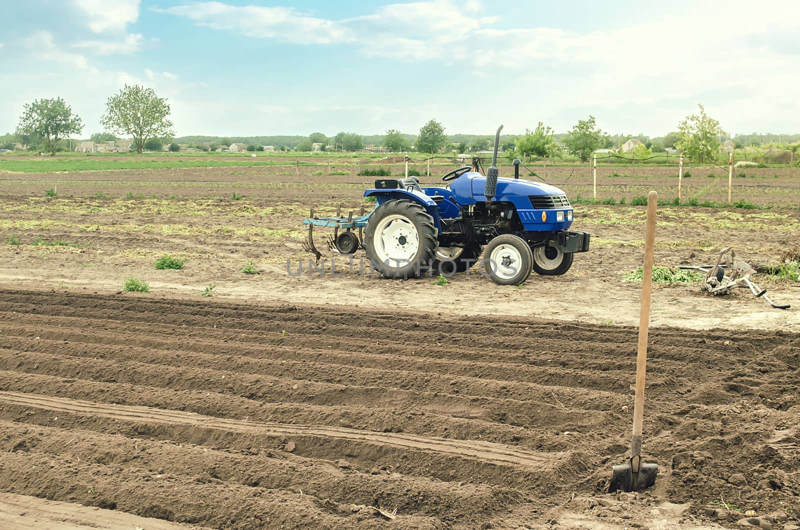 A farm tractor is standing on the field. Preparing the land for planting future crop plants. Cultivation of soil for planting. Agroindustry, agribusiness. Farming, european farmland. Rural countryside