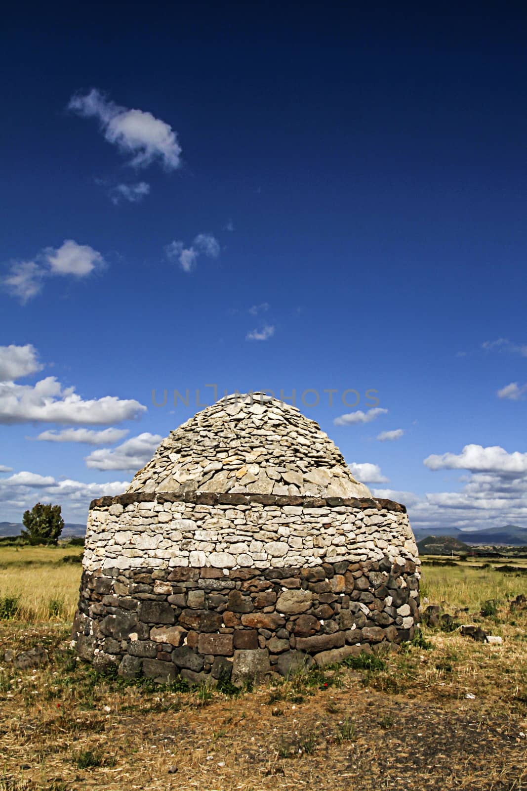 An ancient stone construction, a Sardinian nuraghe, stands out a by robbyfontanesi