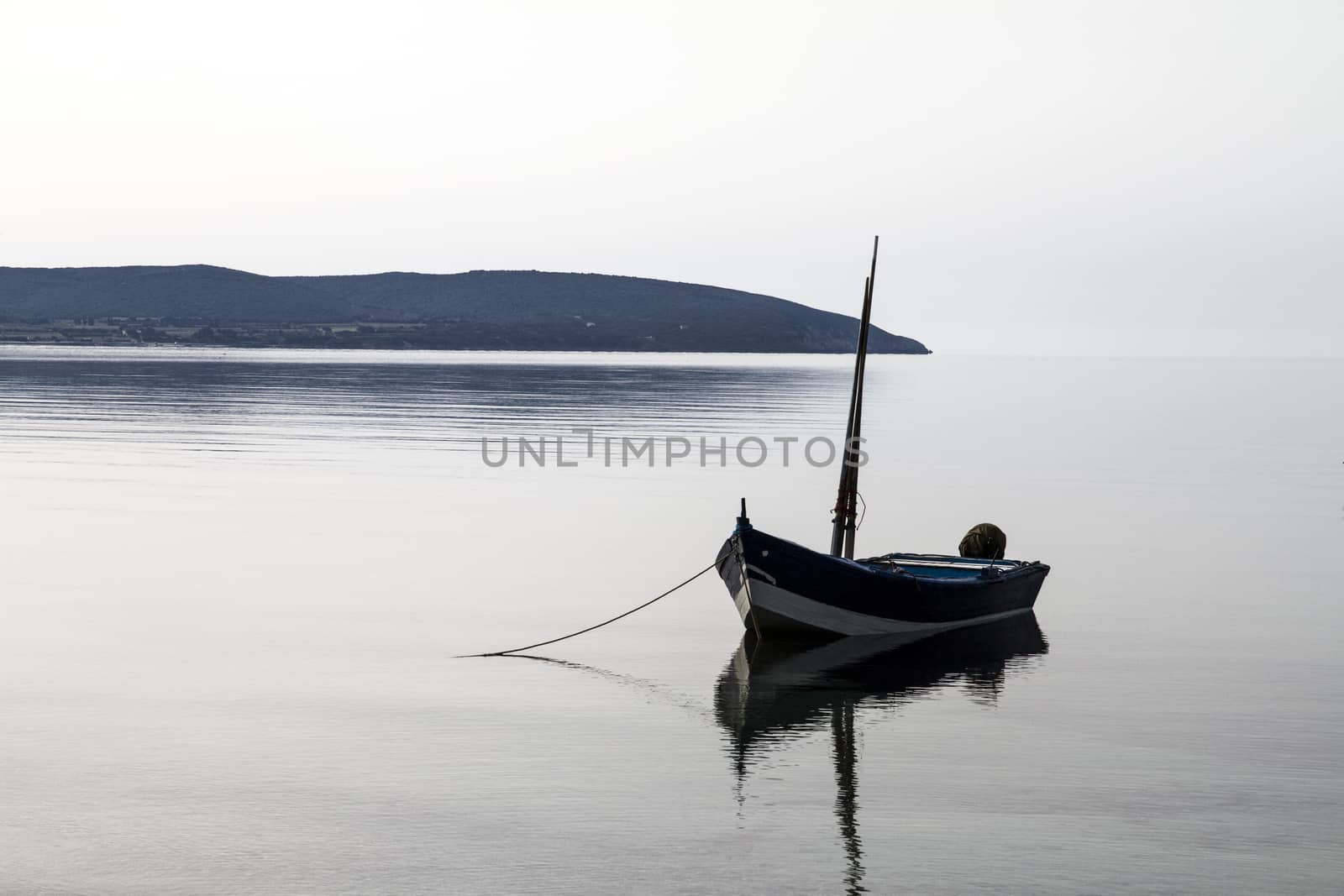 Fishing boat anchored in a sea bay with flat water that merges w by robbyfontanesi