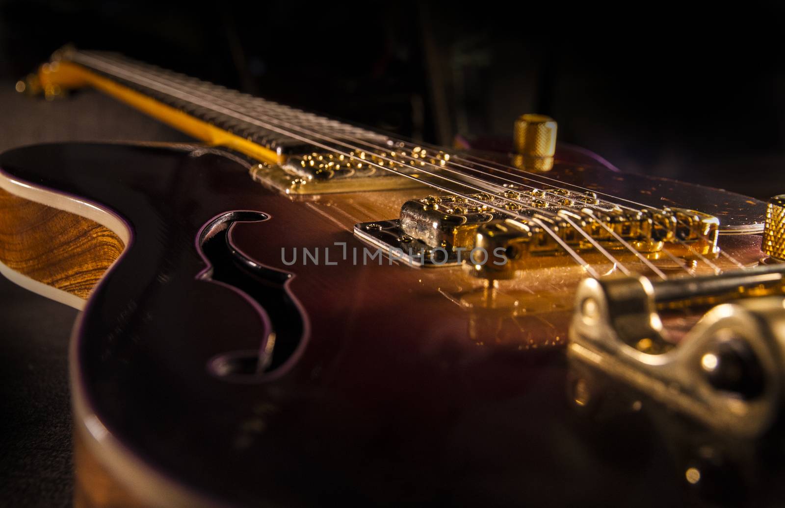 Closeup of sunburst electric guitar with brass mechanics and bright colors on a dark shaded background