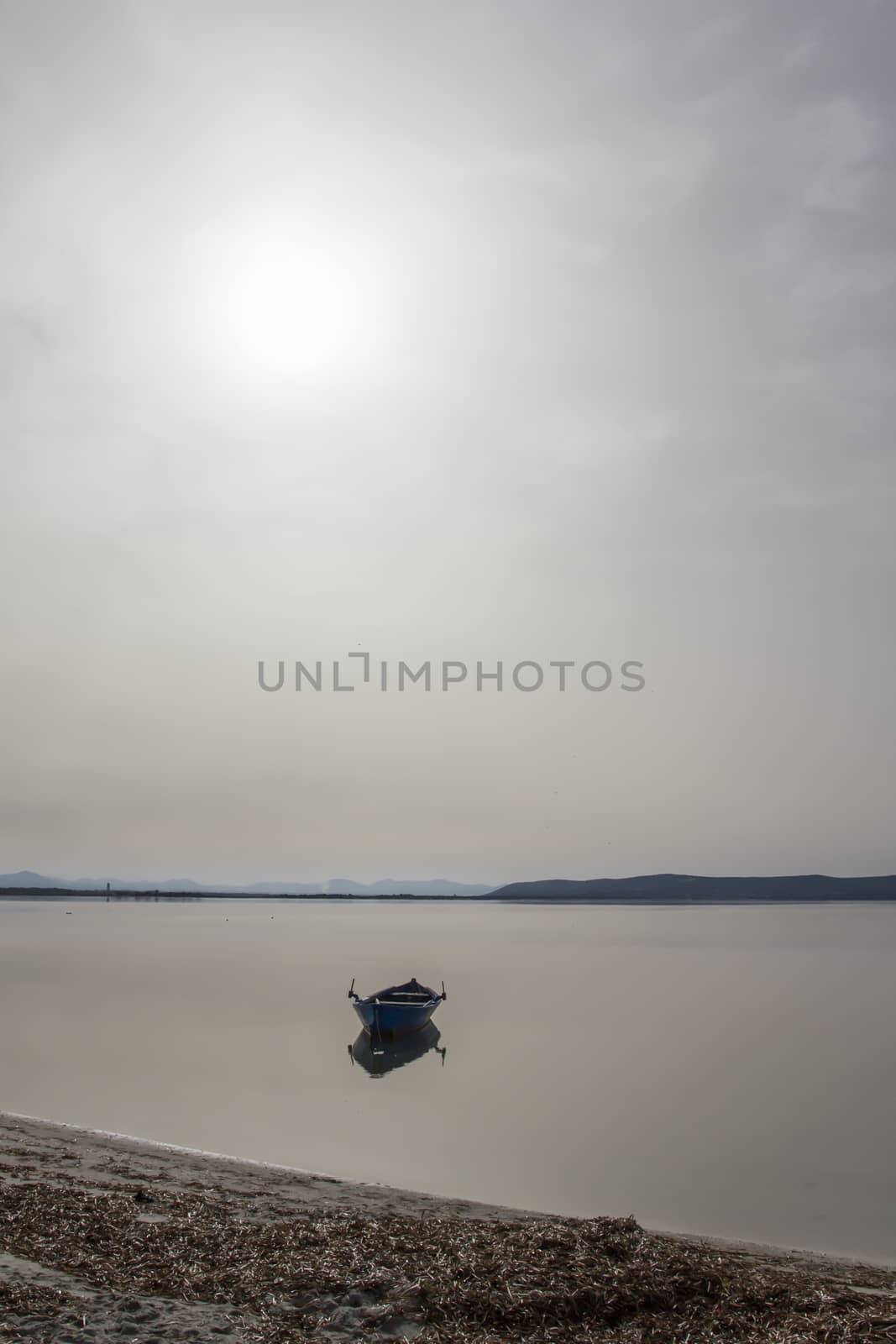 Fishing boat anchored in a sea bay with flat water that merges w by robbyfontanesi