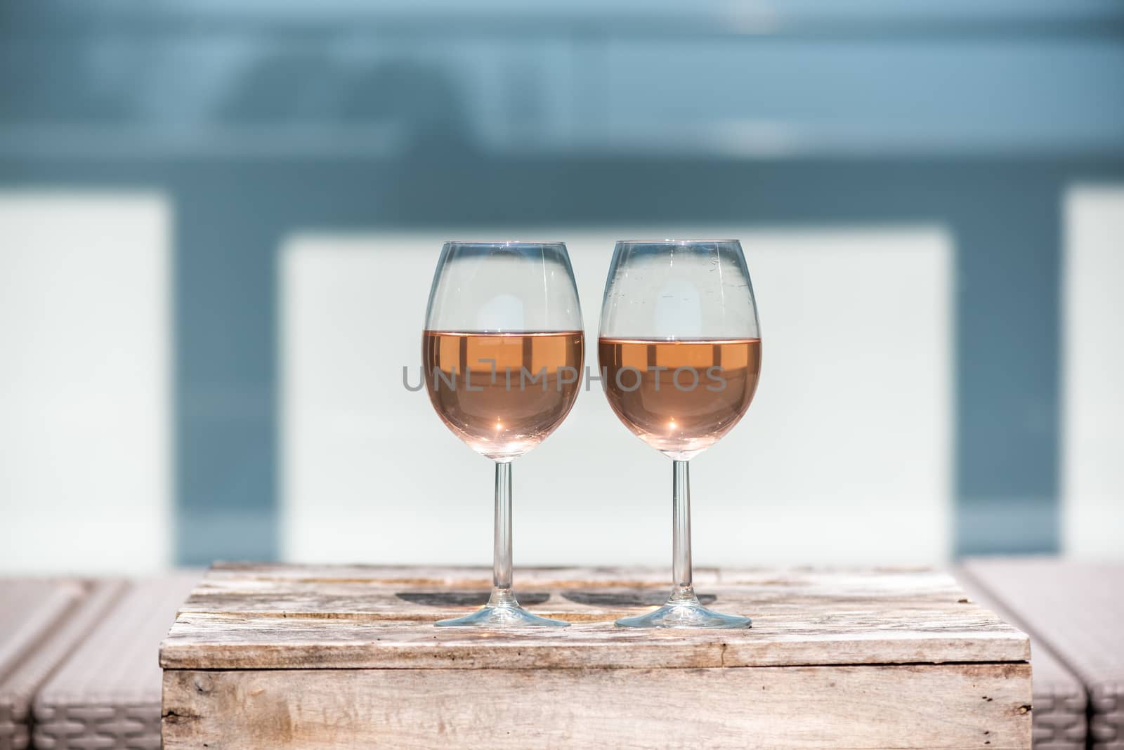 Two rose wine glasses on a small wooden table by LP2Studio