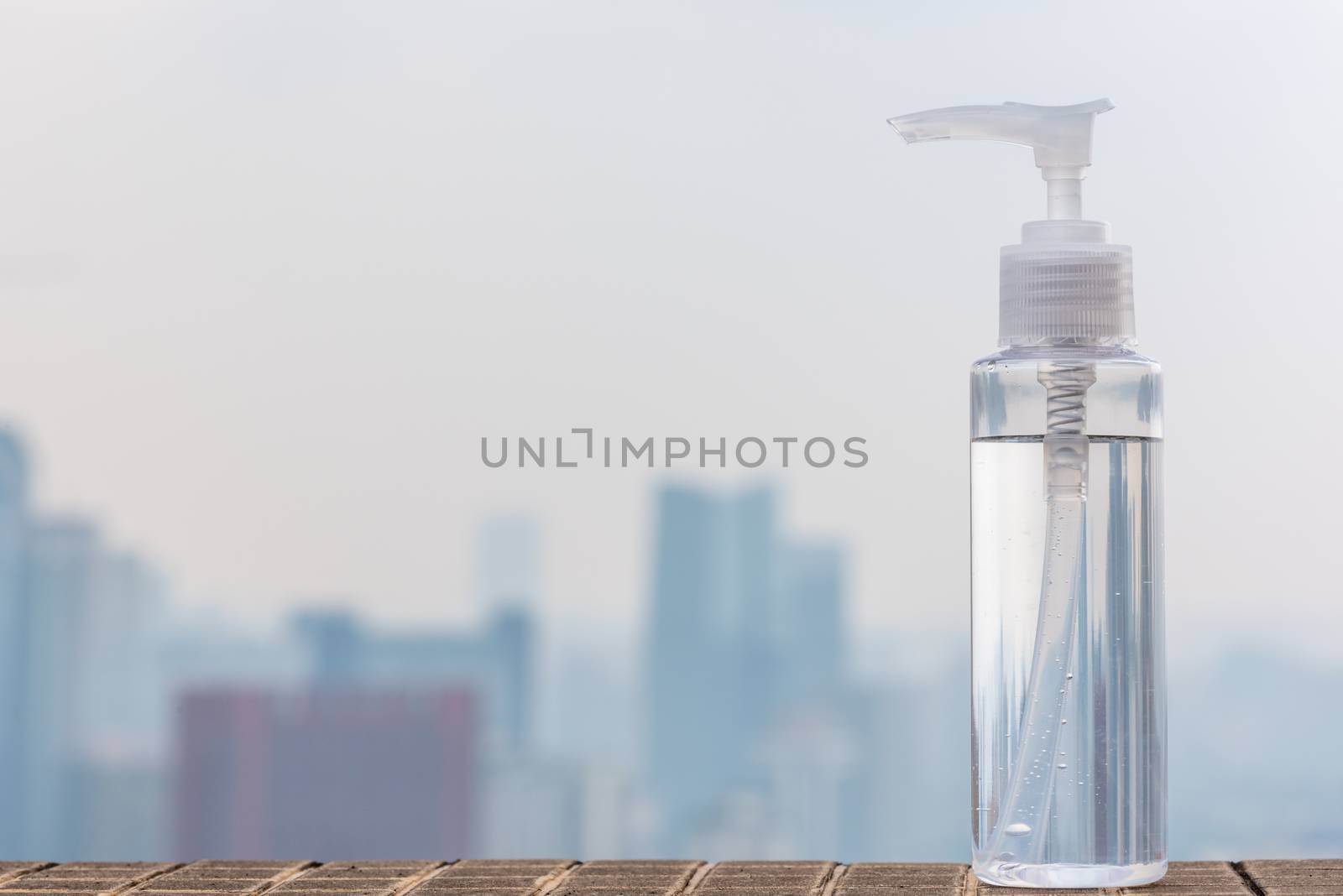 Hand sanitizer container against out of focus city skyline aerial view