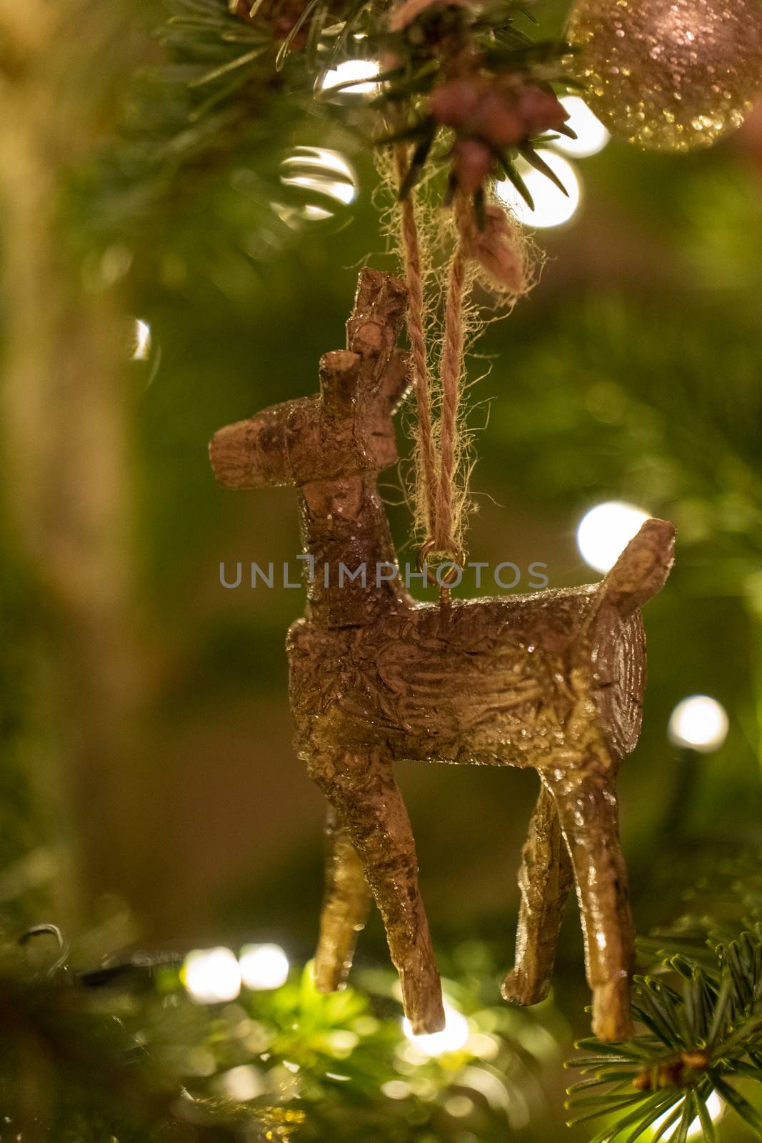 A wooden reindeer shaped Christmas Tree Decoration hanging from a tree