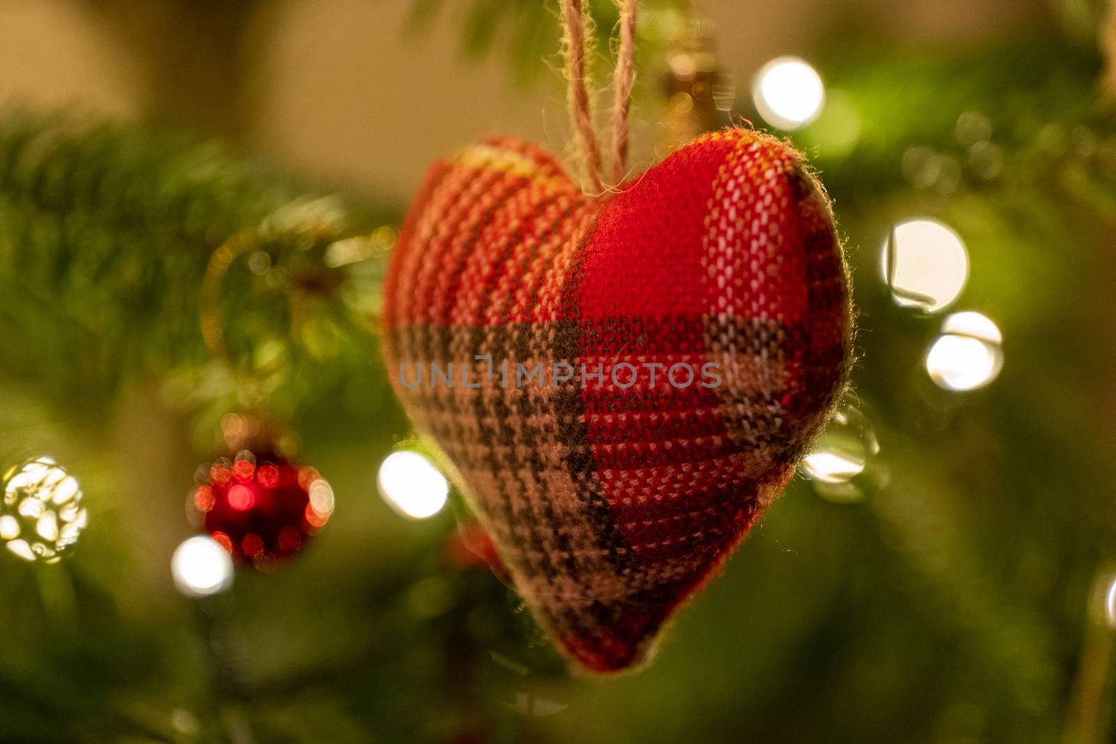 A fabric heart shaped Christmas Tree Decoration hanging from a tree