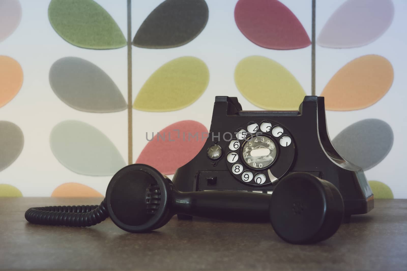 Old retro and vintage phone off the hook against colorful wallpaper by kb79