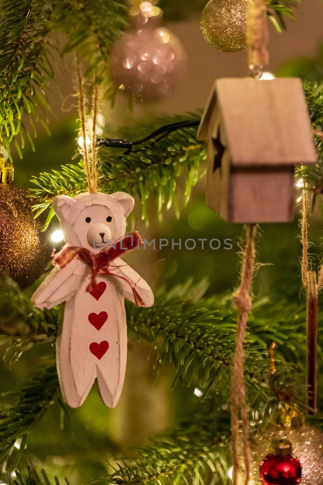 A white wooden bear shaped Christmas Tree Decoration hanging from a tree
