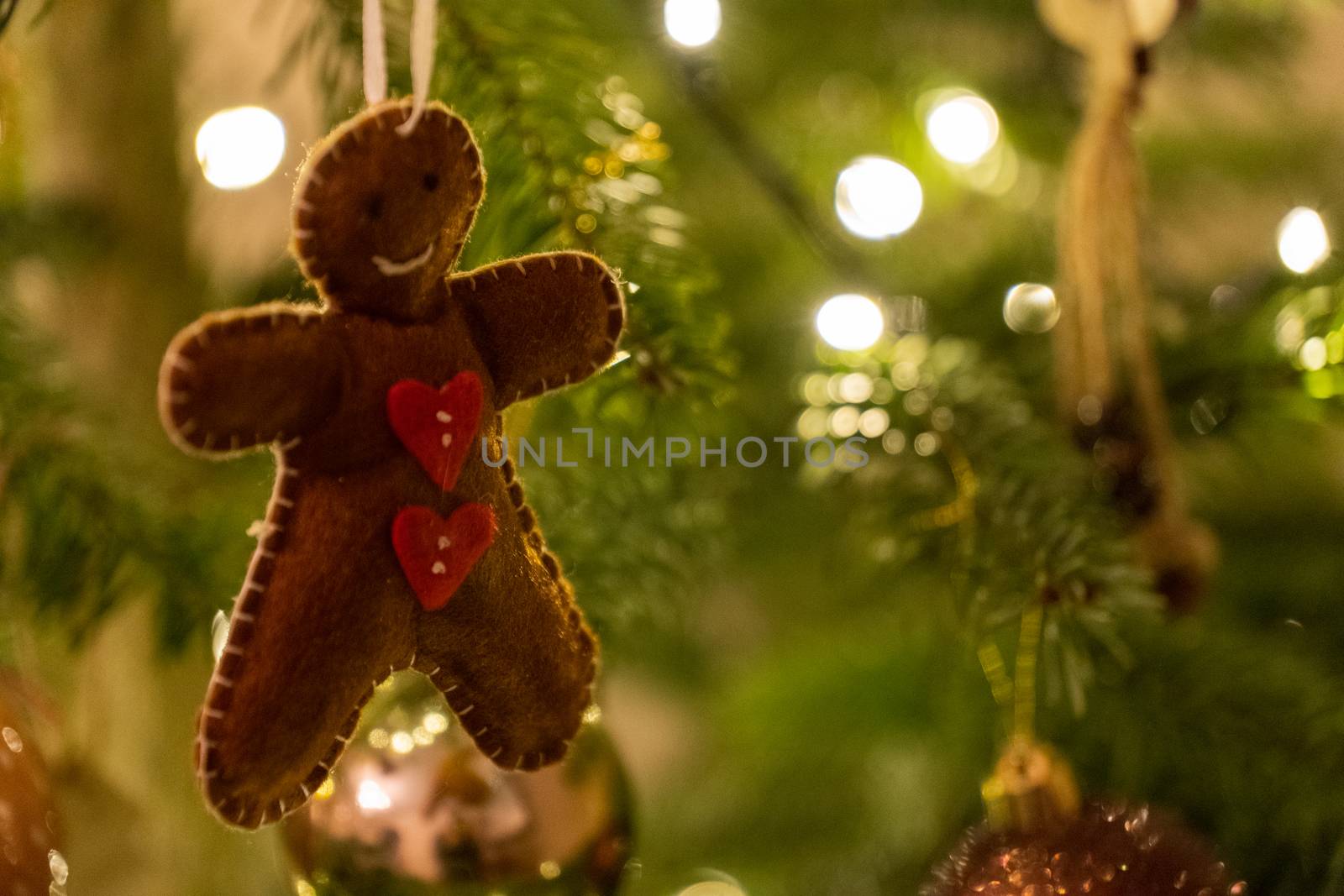 A fabric gingerbread man woman bear shaped Christmas Tree Decoration hanging from a tree