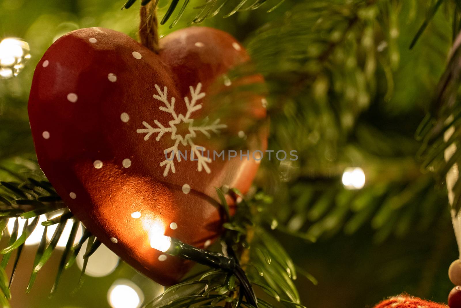 A red wooden heart shaped Christmas Tree Decoration hanging from a tree