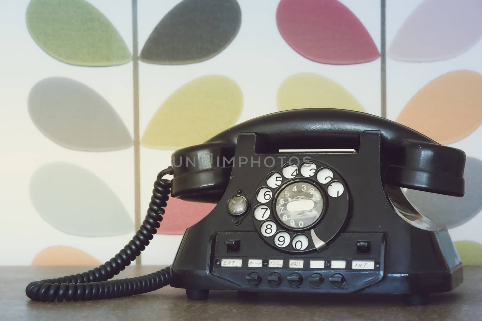 Old retro and vintage phone against colorful wallpaper. Muted processing