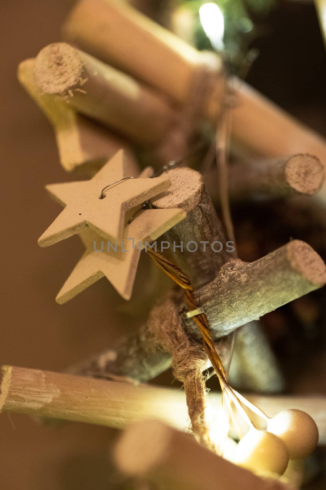 A wooden star shaped Christmas Tree Decoration hanging from a tree