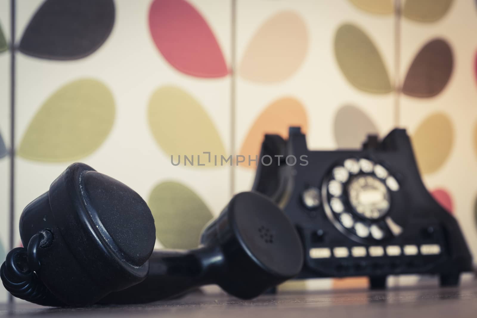Old retro and vintage rotary phone off the hook, colorful wallpaper, selective focus by kb79