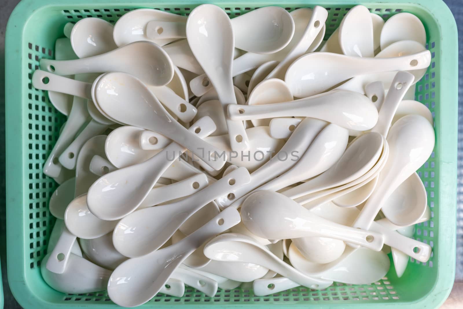 Stack of ceramic spoons for soup in a green bascket