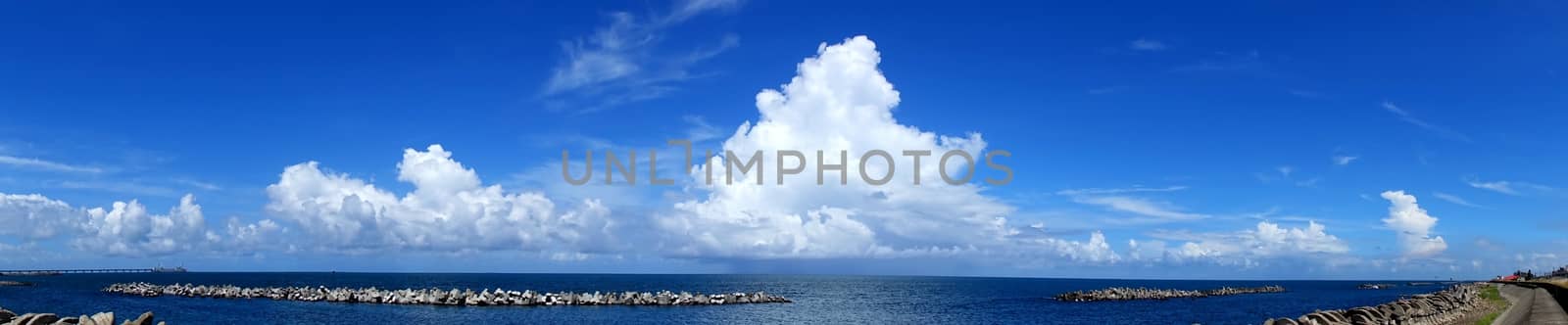 Beautiful panorama of ocean and sky and clouds with concrete breakwaters