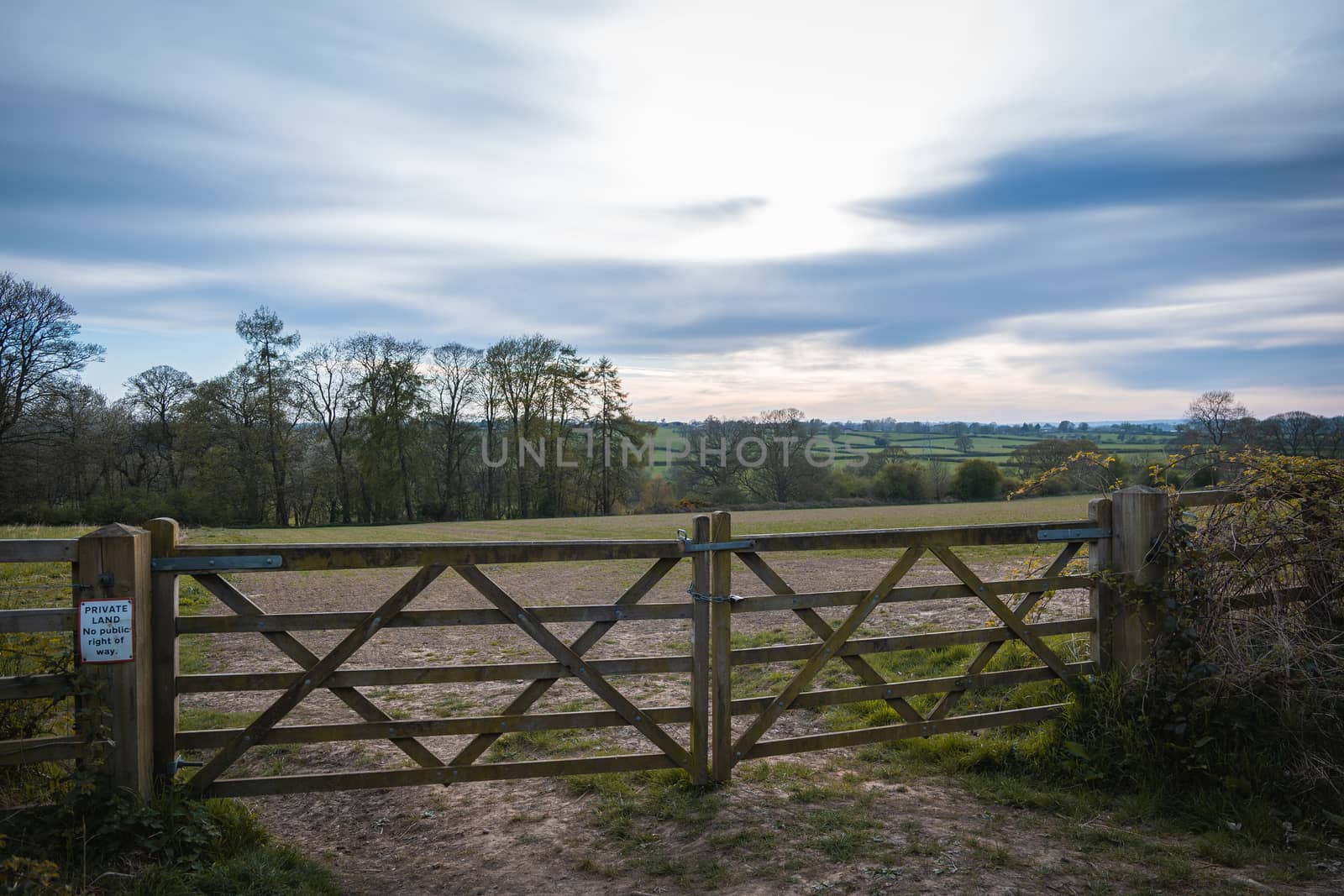 An old rustic wooden farm gate and a beautiful countryside landscape and colorful sky
