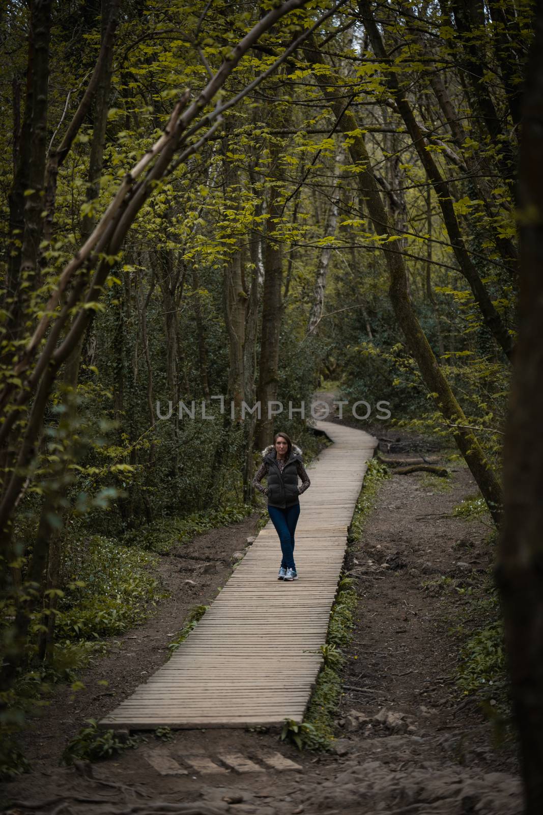 A young woman stood on a wooden pavement path in the countryside