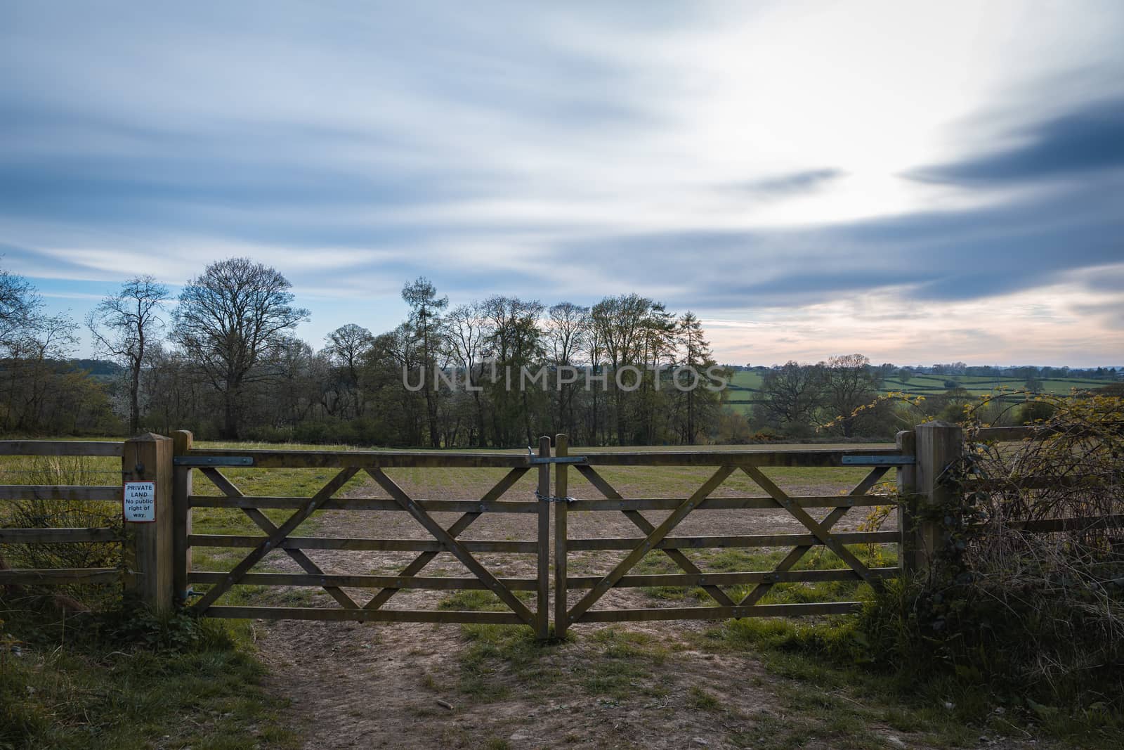 An old rustic wooden farm gate and a beautiful countryside landscape and colorful sky