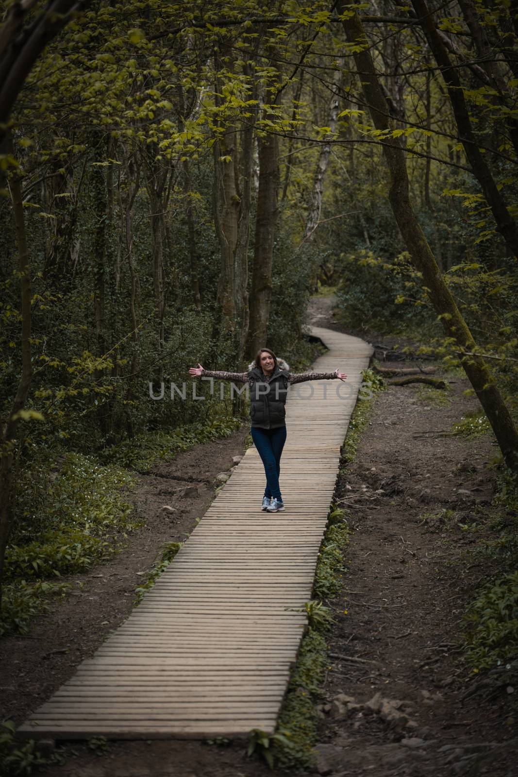 A young woman stood on a wooden pavement path in the countryside