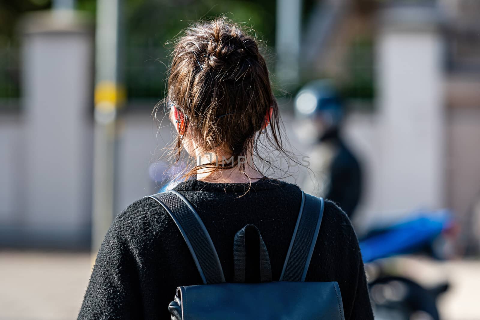 Back view of young woman with backpack on a blurred street background