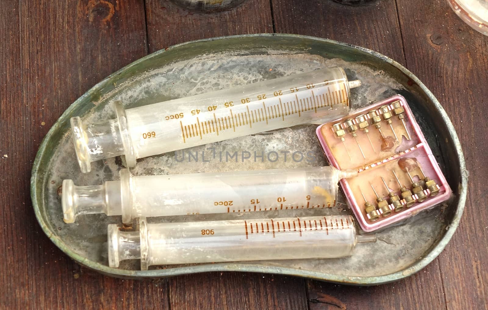 Old medical syringes and hypodermic needles in corroded tray
