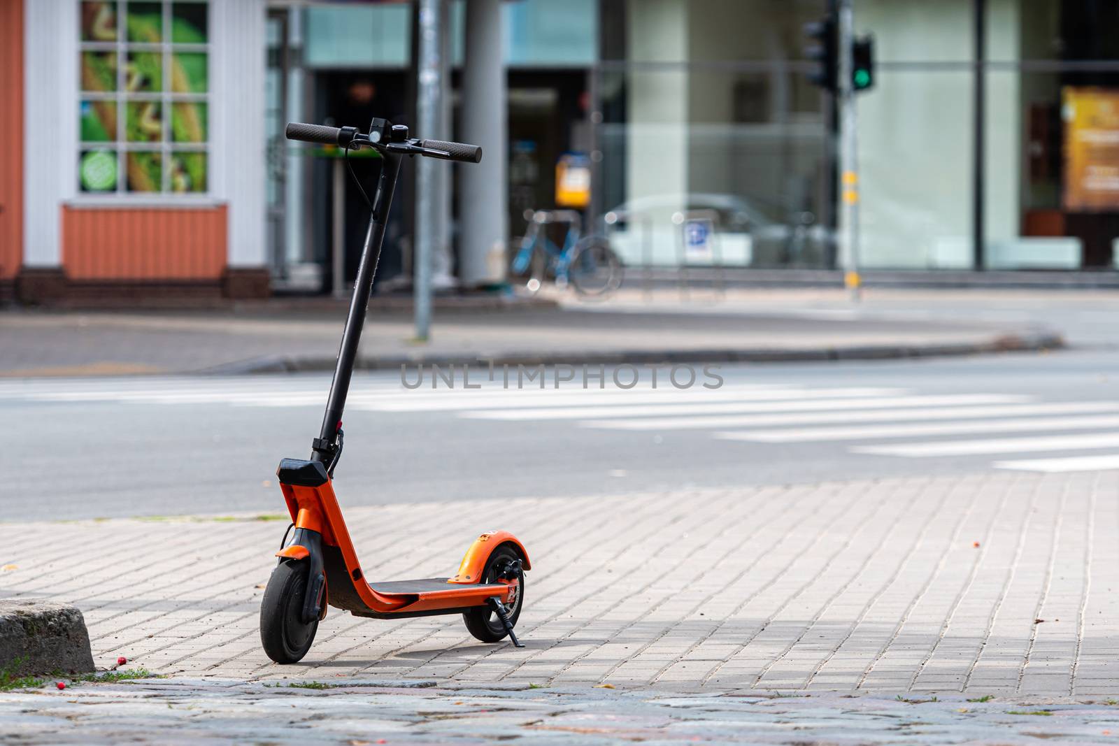 electric scooter or e-scooter parked on sidewalk, blurred city street background - image