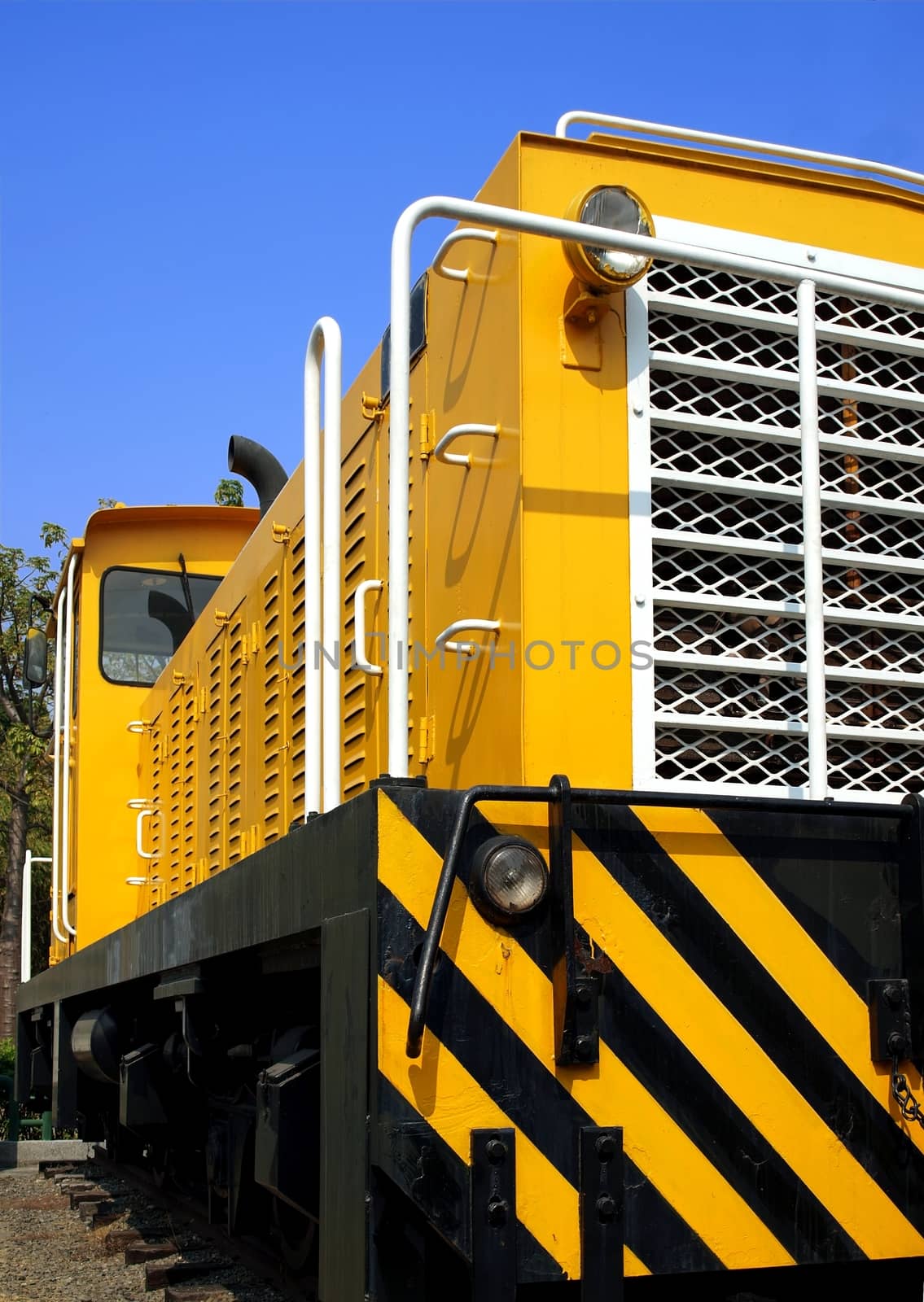 A bright yellow vintage diesel engine designed for narrow railway gauge