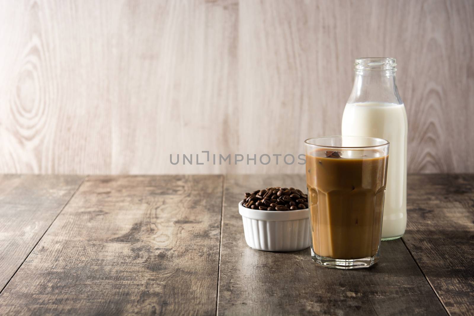 Iced coffee or caffe latte in tall glass on wooden table.