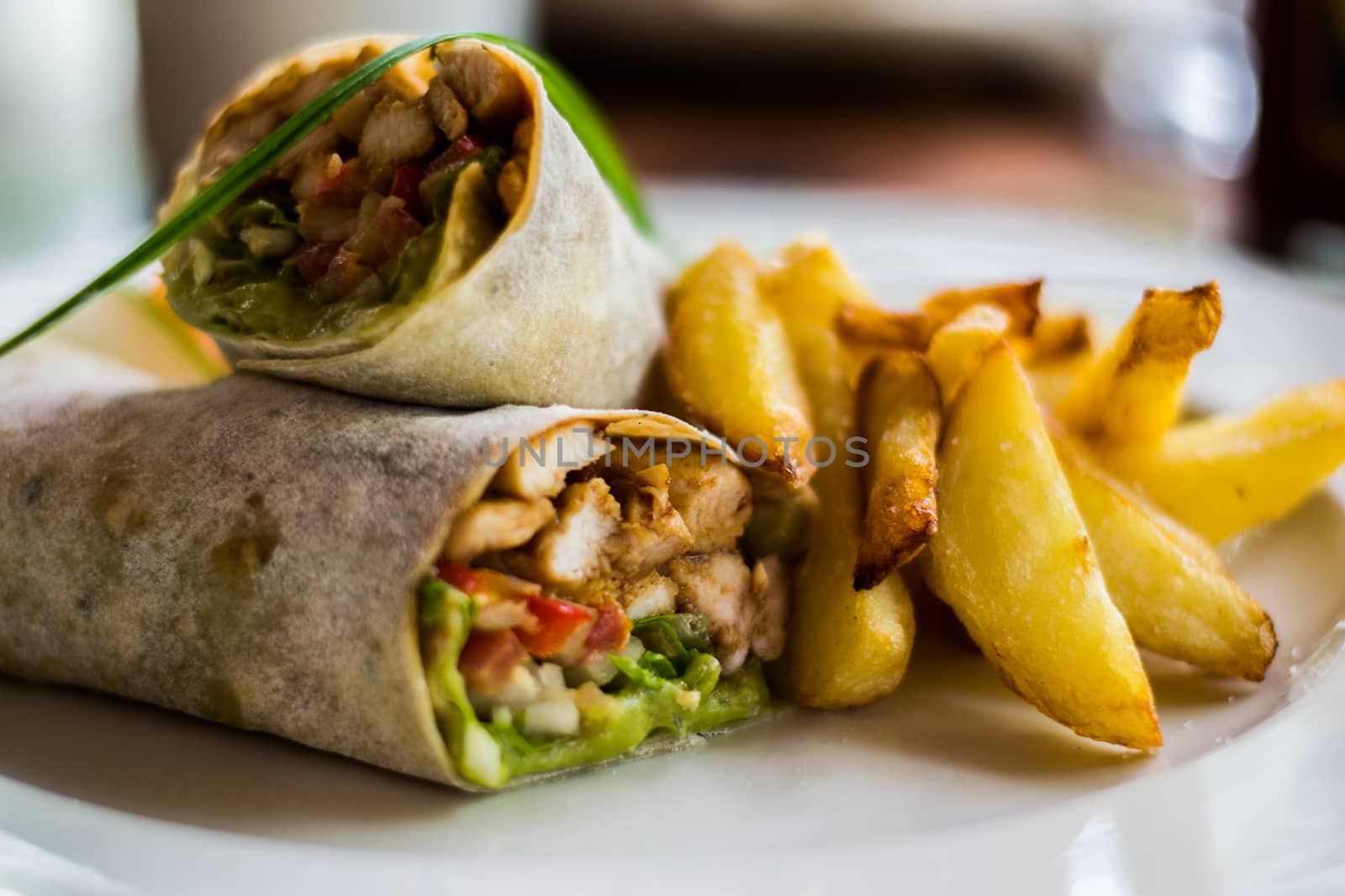 Tasty wraps with chicken, avocado, lettuce and french fries on a plate. Selective focus