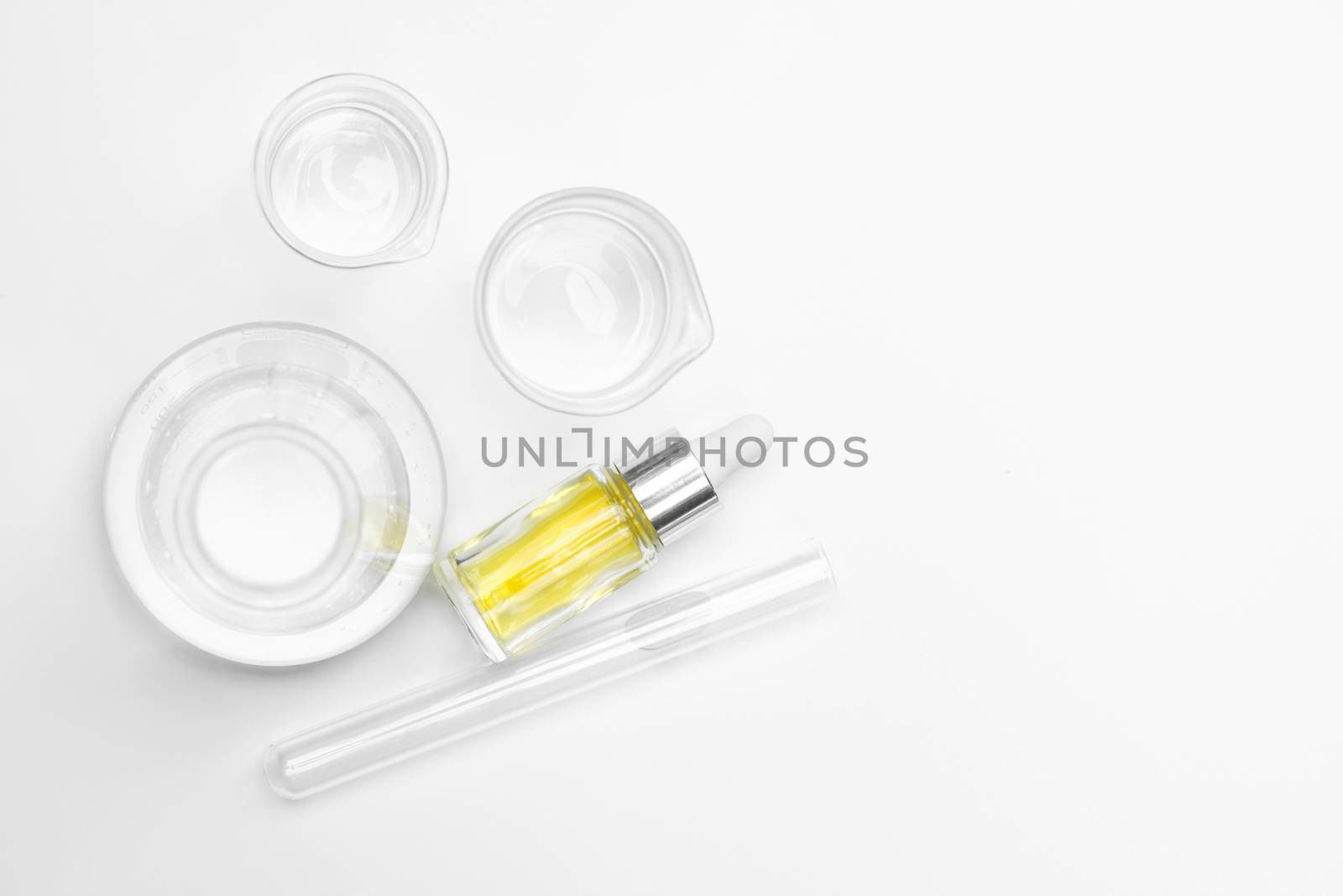 Yellow cosmetic liquid (oil). Chemicals for beauty care on white laboratory table. (Top View)