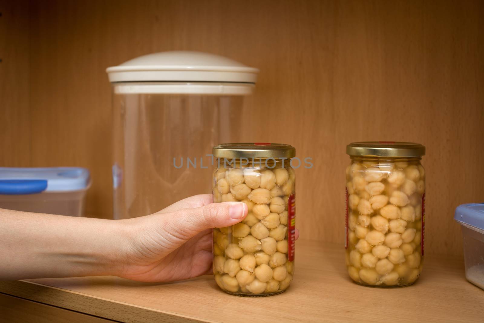 woman picking up a pot of chickpeas from the kitchen pantry