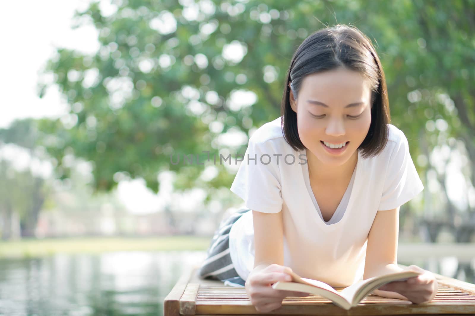 woman reading book in deck chair near swimming pool by ekachailo