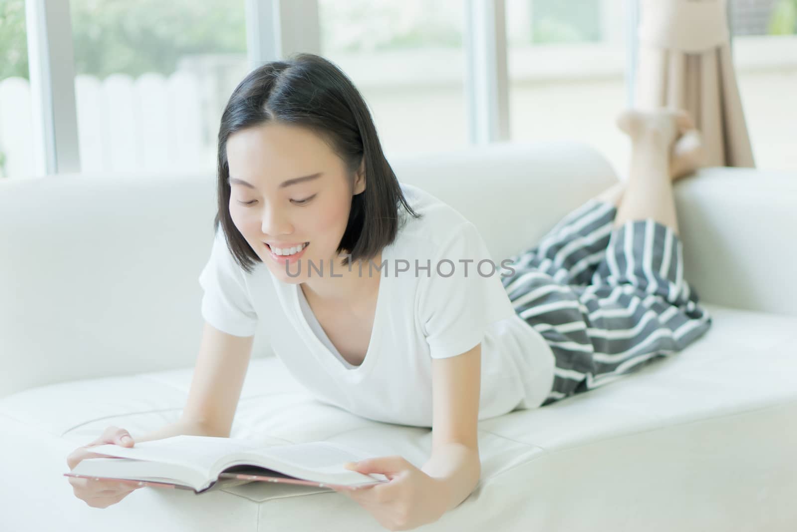 Woman reading a book on a sofa by ekachailo