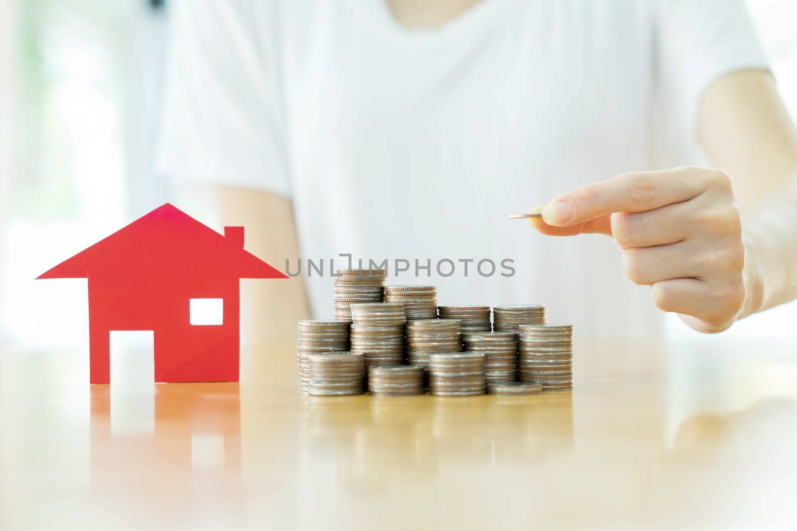 woman put coins to stack of coins and red house blackground