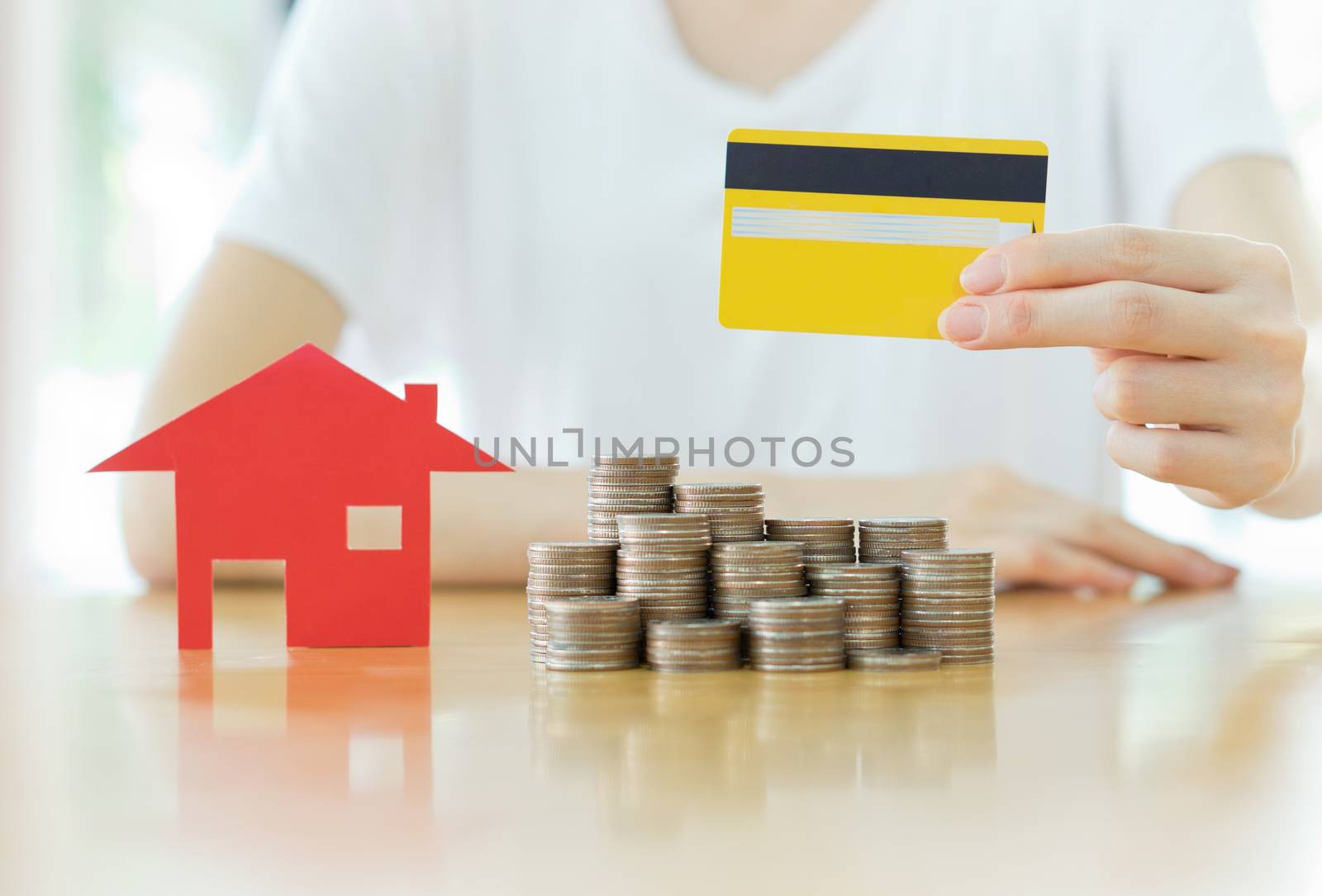 Real estate investment by credit card. House and coins on table.