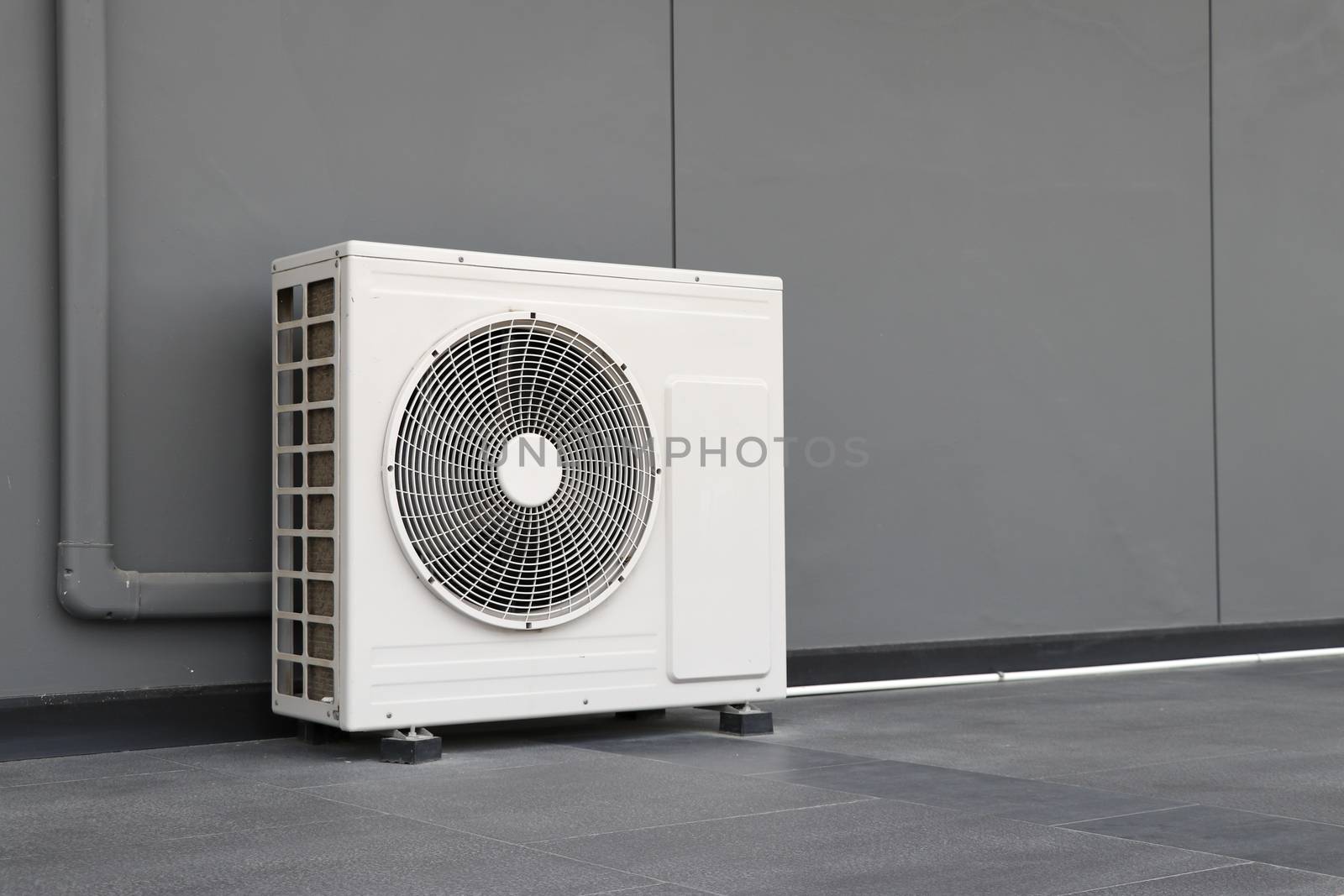 Condensing unit of air conditioning systems. Condensing unit installed on the gray wall.